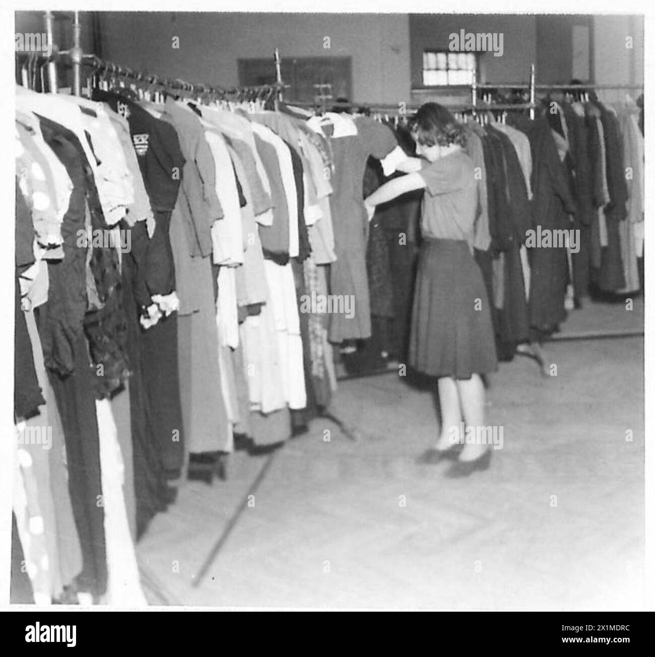 Un assistant de magasin organise et distribue des vêtements provenant de rayonnages à Athènes sous la supervision de l'armée britannique. Banque D'Images