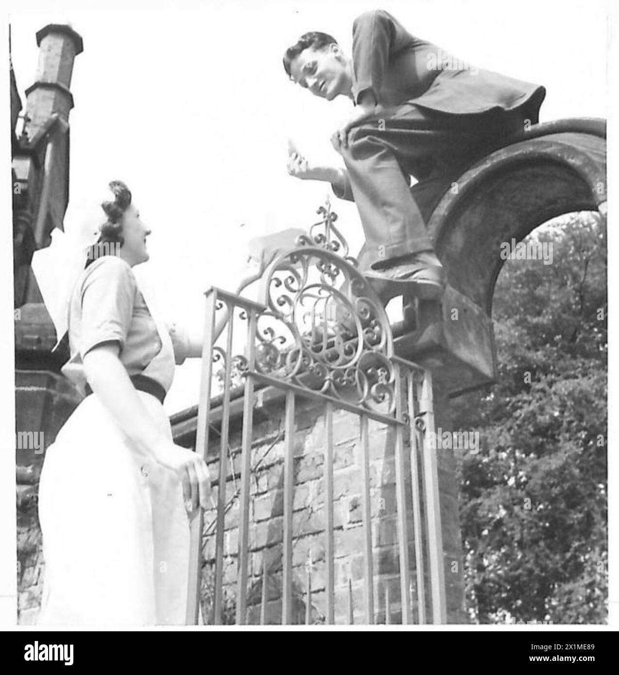 Un patient servi par la Croix-Rouge britannique et par John War Organisation profite d'un thé dînatoire assis sur un mur, illustrant la vie hospitalière en temps de guerre. Banque D'Images