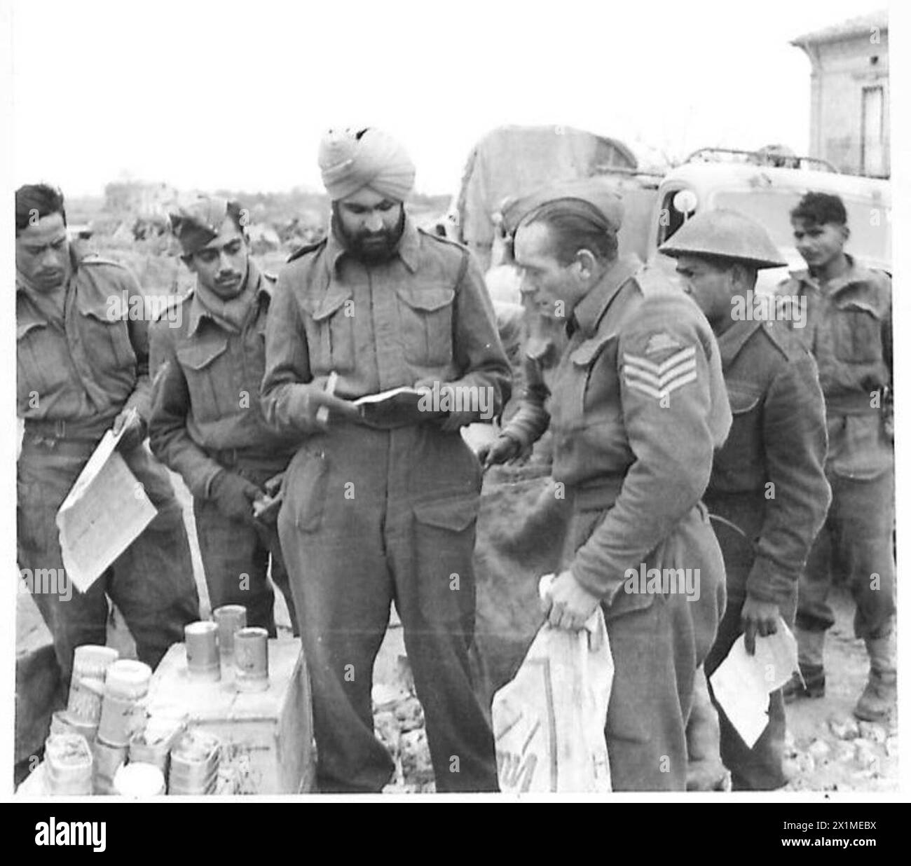 ITALIE : HUITIÈME ARMYWITH LE ROYAL INDIAN ARMY SERVICE CORPS - Sgt. Cargill, 3rd Field Regiment, R.A. d'Arbroath, Écosse, reçoit son numéro de conserves de l/NK. Schan Singh de Jullunder City, Punjab, armée britannique Banque D'Images