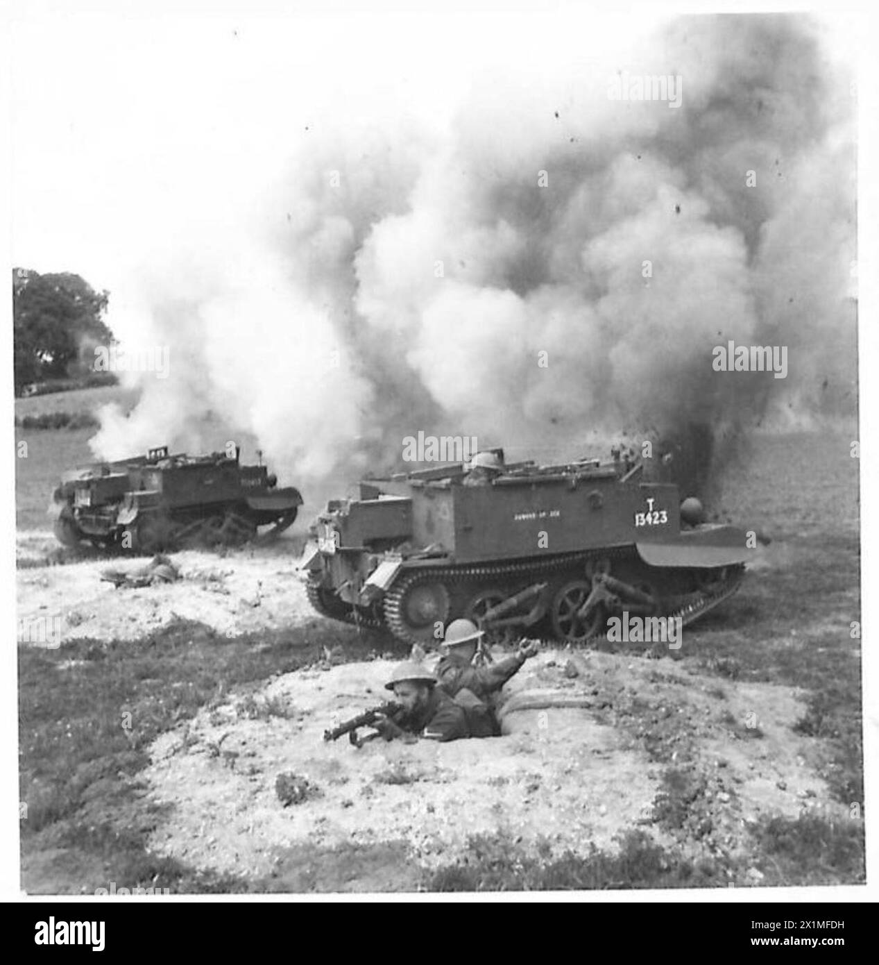 Les soldats du Royal Berkshire Regiment s'entraînent dans des tranchées fendues, engageant des porte-avions Bren avec des fusils et des grenades, tandis que de fausses explosions et des écrans de fumée simulent les conditions de bataille. Banque D'Images