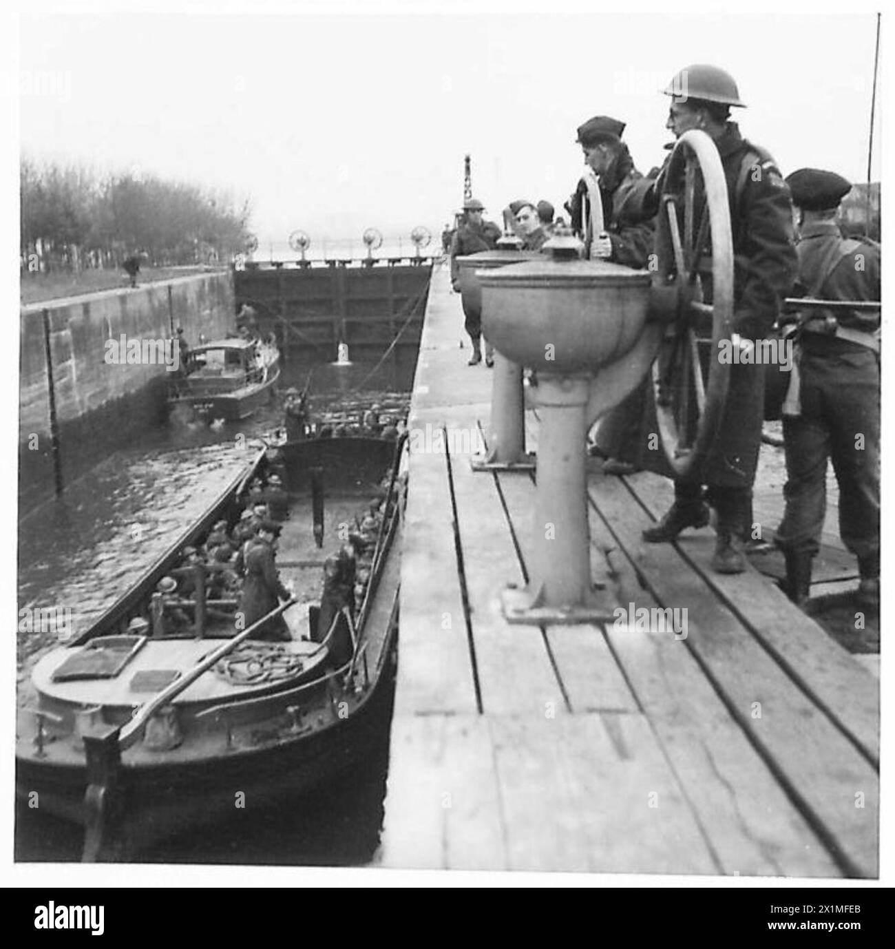 Les Home Guards opèrent le long des voies navigables intérieures lorsque les portes d'écluse s'ouvrent, permettant le passage d'une embarcation et d'une barge. Le personnel de l'armée britannique supervise l'opération. Banque D'Images