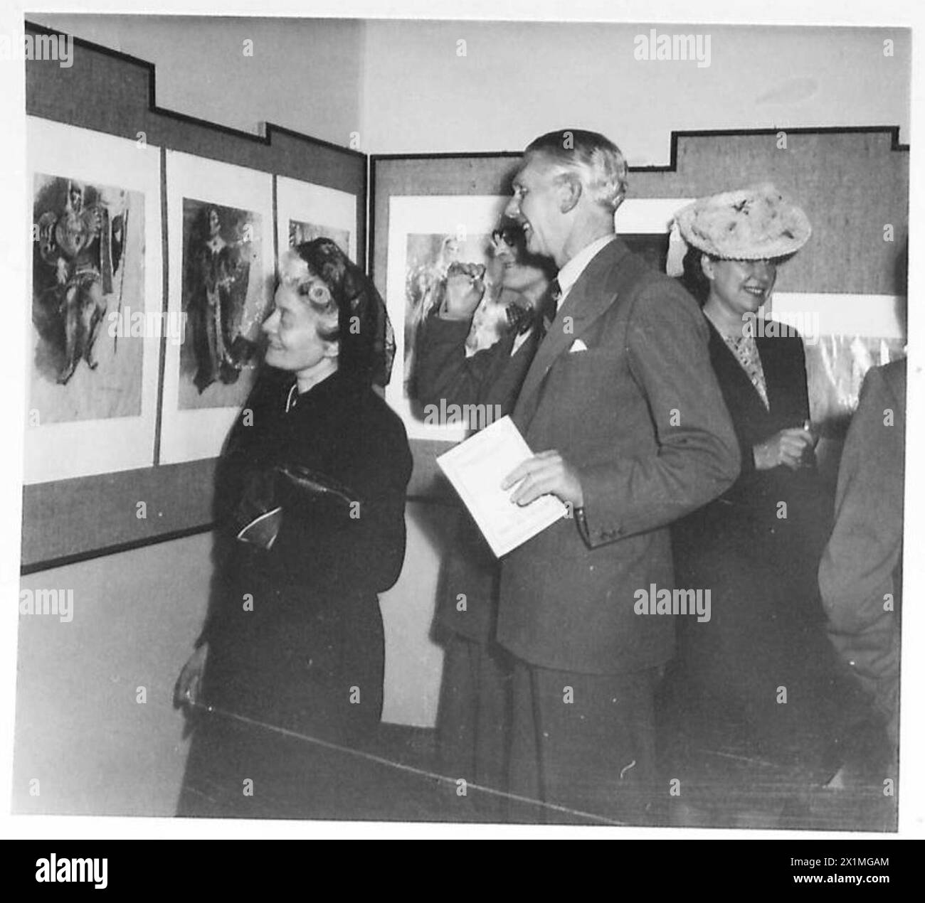 Les visiteurs examinent des peintures lors d'une exposition de livres du British Council, observée par le personnel de l'armée britannique. Banque D'Images