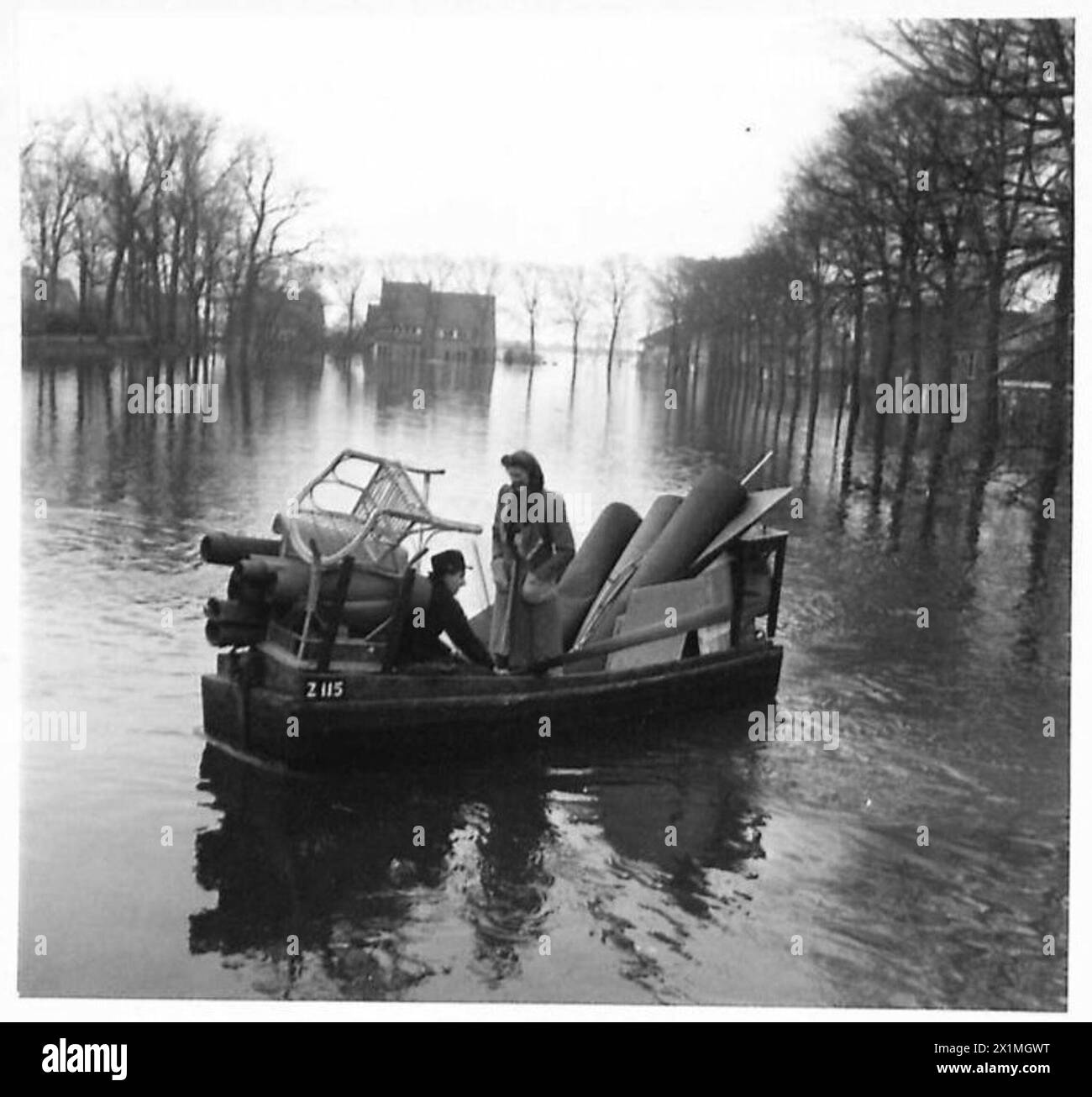 Un mari et sa femme pagayent un bateau rempli de meubles récupérés pour atteindre la terre ferme sur l'île inondée de Walcheren, à la recherche d'un nouveau logement, 21e groupe d'armées, armée britannique. Banque D'Images