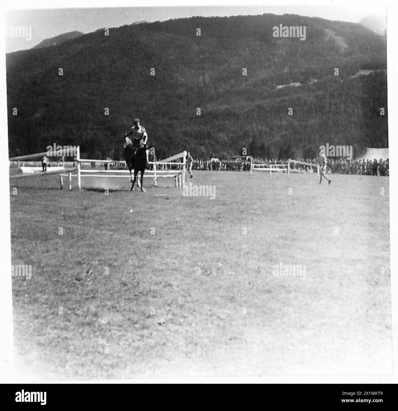 Un cheval réussit à franchir un saut lors d'une réunion de course en Autriche, observée par le personnel de l'armée britannique. Banque D'Images