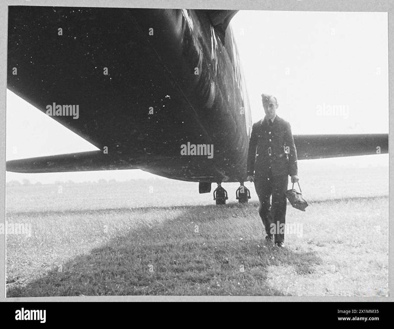 Le personnel au sol de la RAF déplace le magazine d'un bombardier à la section photographique à la suite d'un raid, gérant les opérations post-mission. Banque D'Images