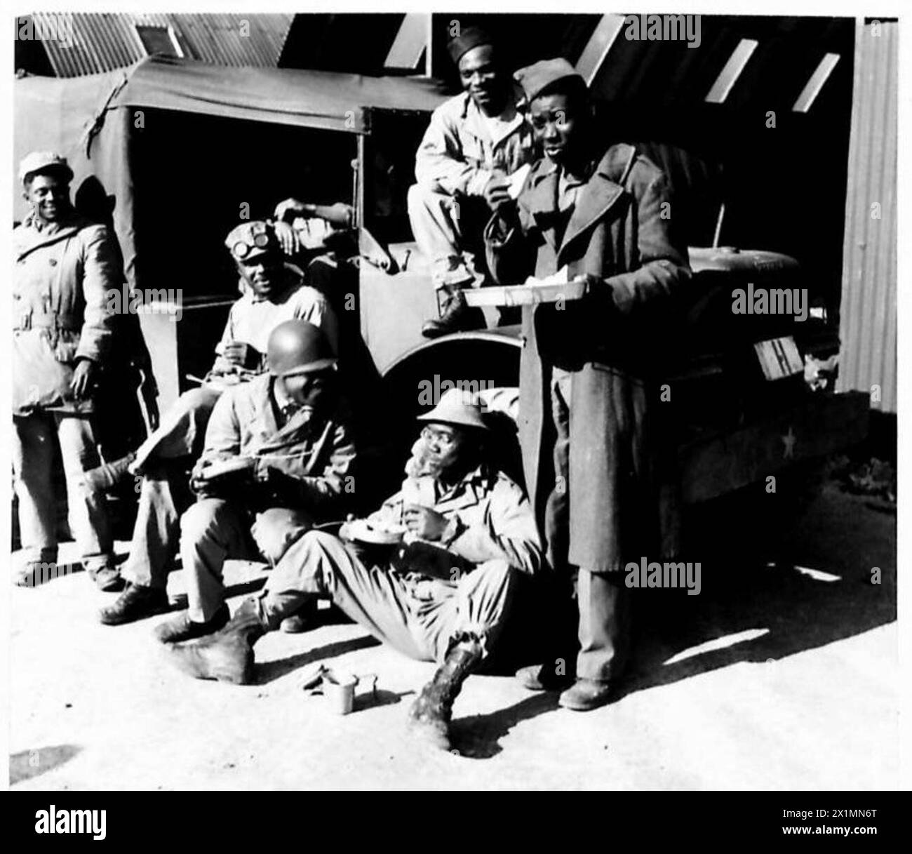 DÉPÔT D'APPROVISIONNEMENT GÉNÉRAL POUR LES MAGASINS ET L'ÉQUIPEMENT AMÉRICAINS - soldats noirs américains travaillant au dépôt ayant leur repas de midi, British Army Banque D'Images