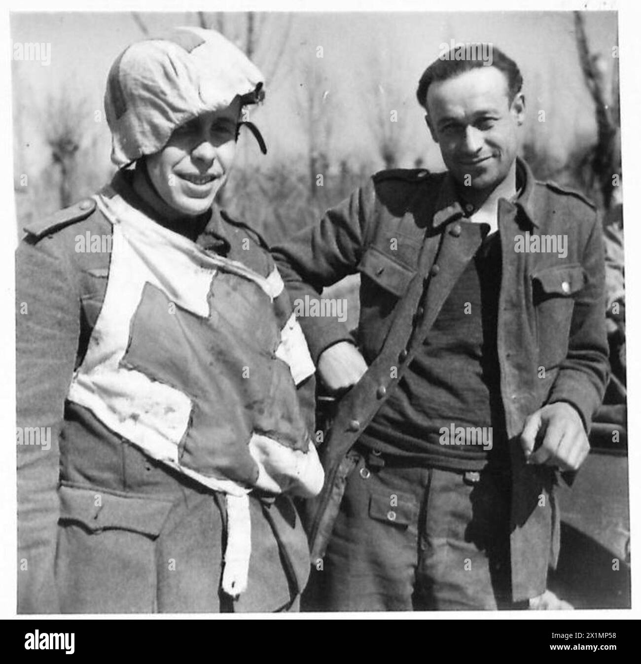 Deux déserteurs de l'armée allemande en Italie, l'un portant des drapeaux de la Croix-Rouge sur sa tunique et son casque, et un Français enrôlé dans le service allemand, sont documentés par l'armée britannique lors de la journée de Patrick par la huitième brigade irlandaise de l'armée. Banque D'Images