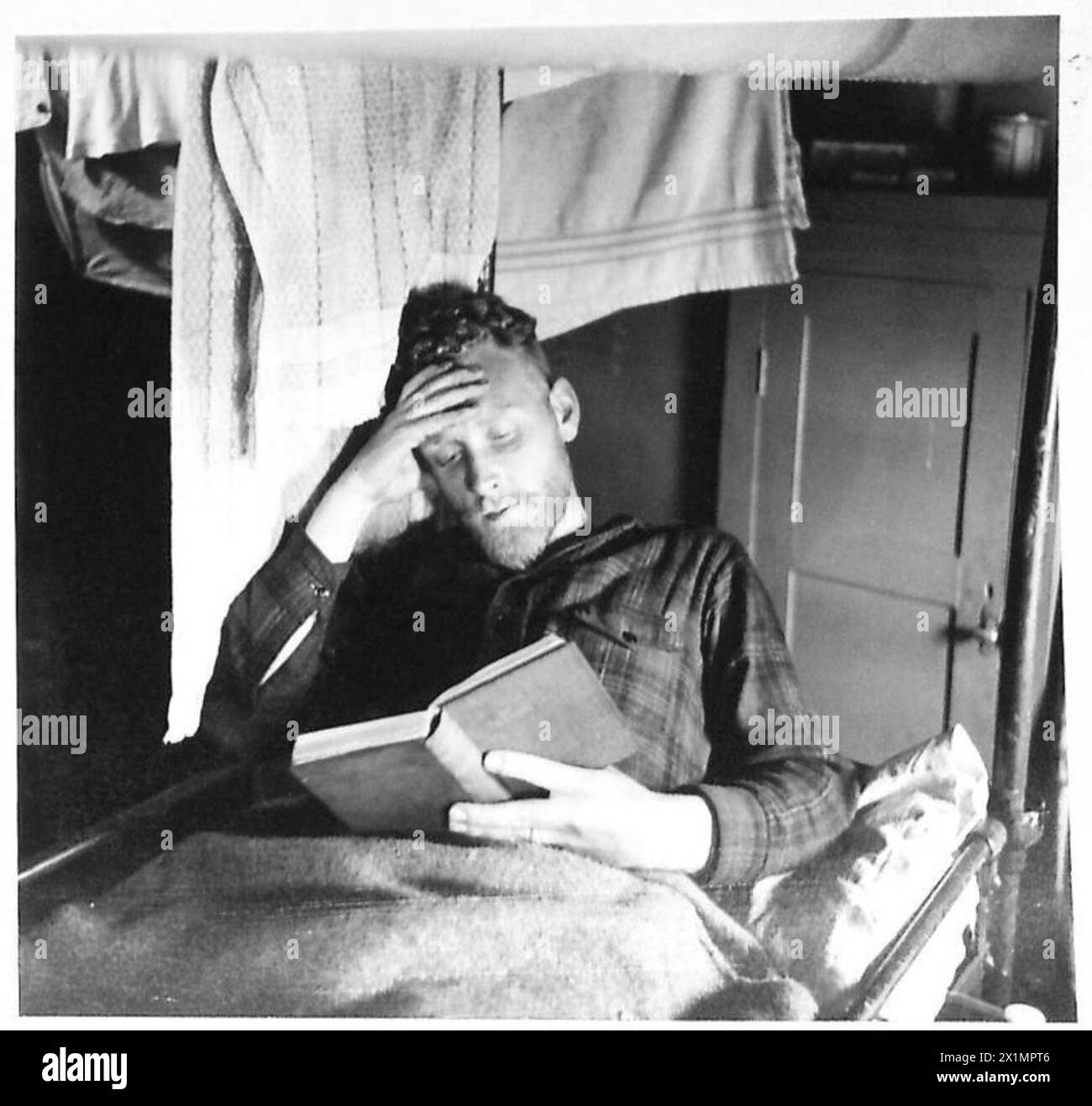 Le matelot ordinaire R. Cromb repose dans sa couchette à bord d'un navire de l'armée britannique à destination de l'Afrique après avoir terminé son service. Banque D'Images