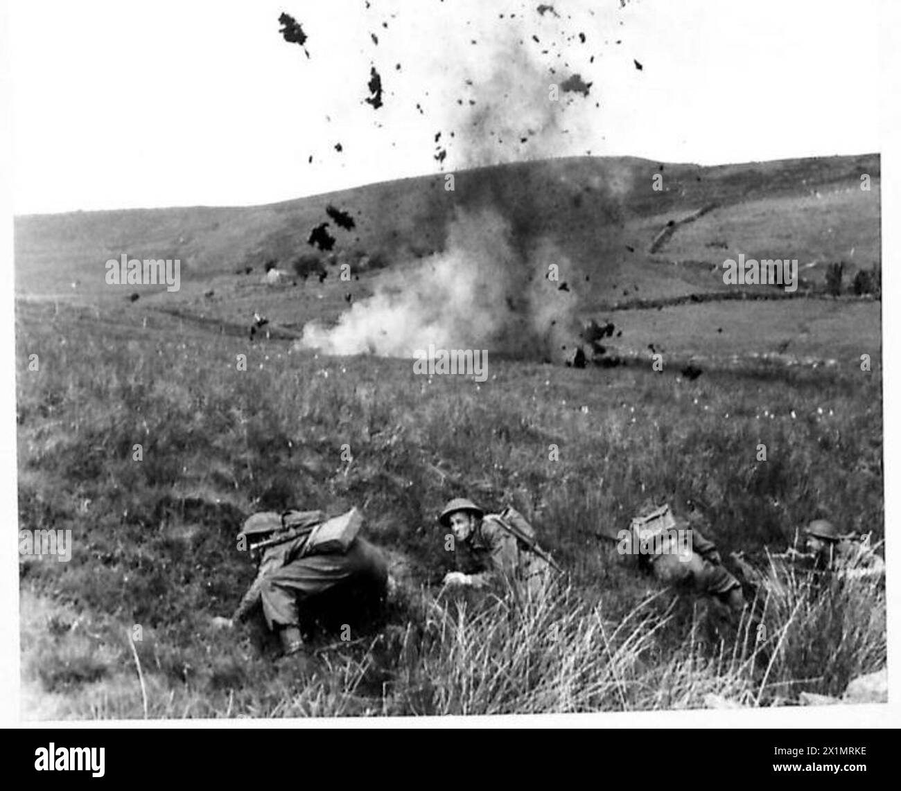 ÉCOLE DE L'EXERCICE DE BATAILLE - avec des charges explosant autour d'eux, les hommes avancent vers le haut de la colline à leur objectif, l'armée britannique Banque D'Images