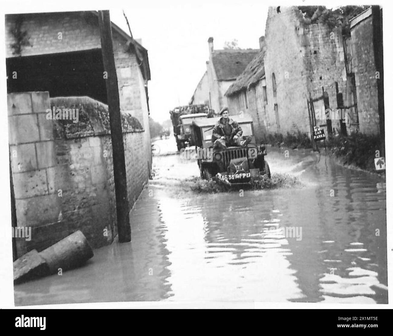 ROUTES INONDÉES EN NORMANDIE - assis sur le capot d'une jeep un soldat est conduit dans une rue inondée, British Army, 21st Army Group Banque D'Images