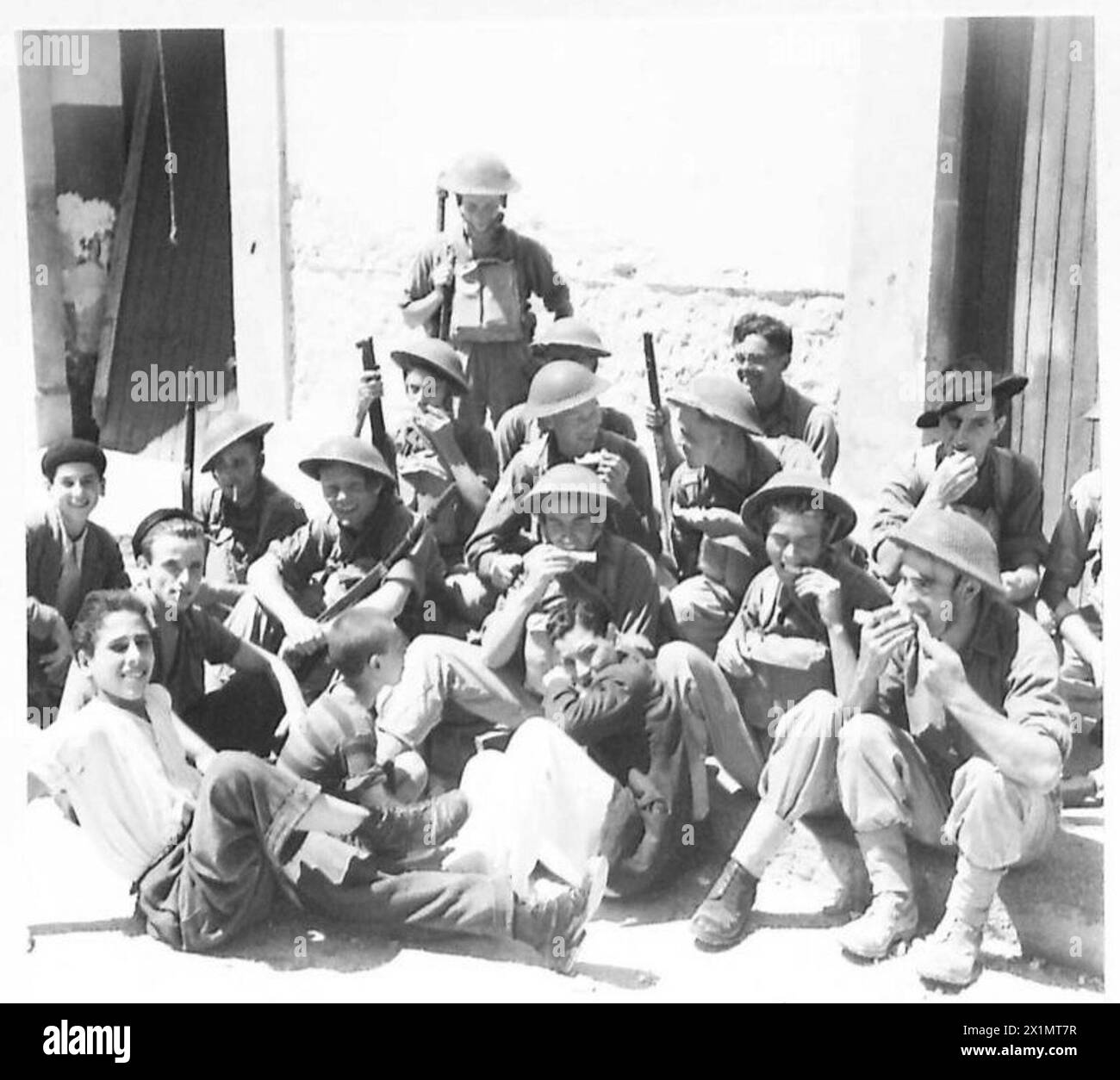 INVASION DE LA SICILE - les troupes britanniques se reposant au bord de la route échantillonnent le melon d'eau et discutent avec des enfants italiens, l'armée britannique Banque D'Images