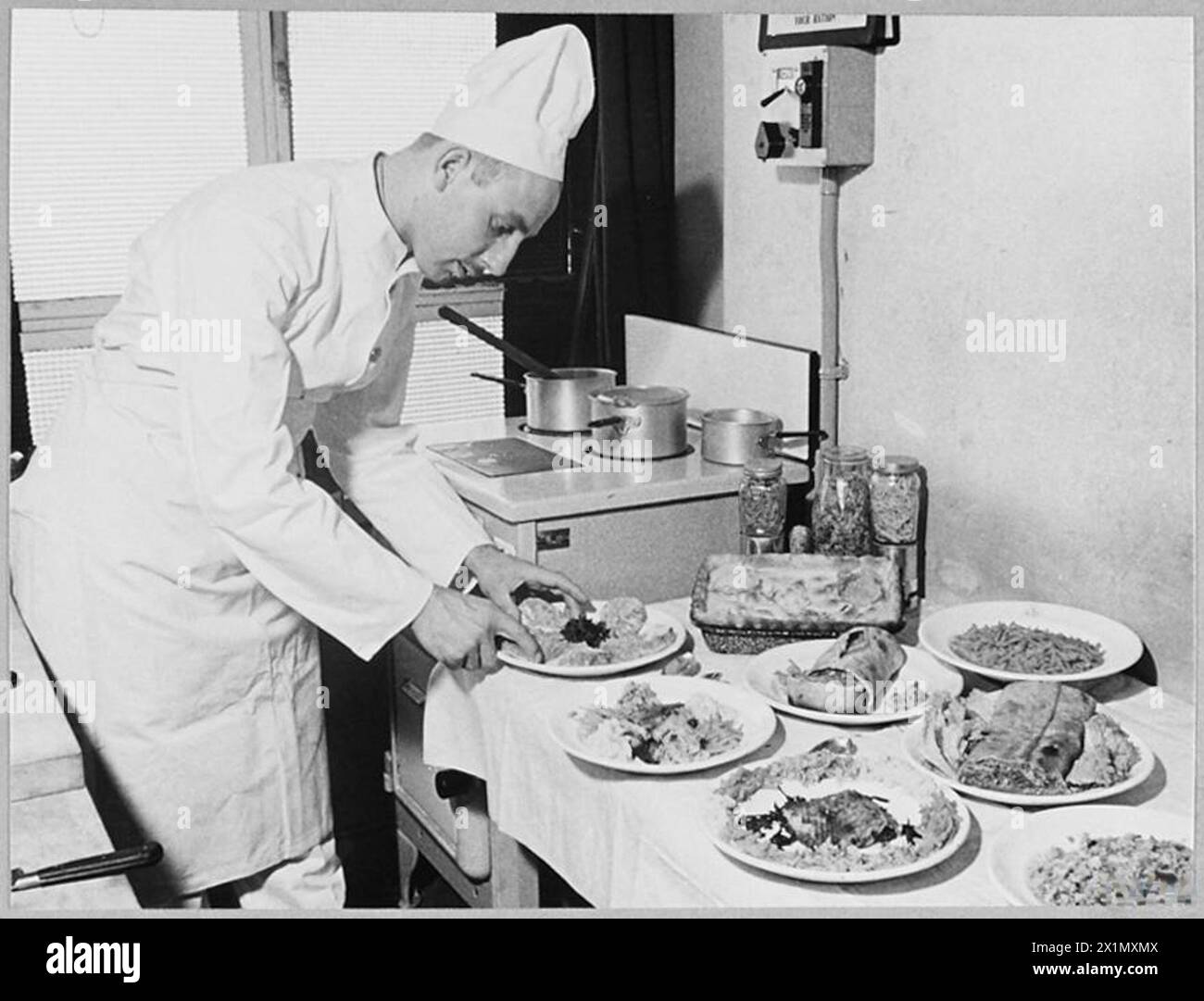 R.A.F. ET W.A.A.F. COOKS ÉTUDIENT LA MEILLEURE FAÇON DE CUISINER EN TEMPS DE GUERRE - (6392). Le cuisinier de cuisine expérimentale du ministère de l'Air met la touche finale aux plats qui seront testés par l'inspecteur en chef de la restauration, Royal Air Force Banque D'Images