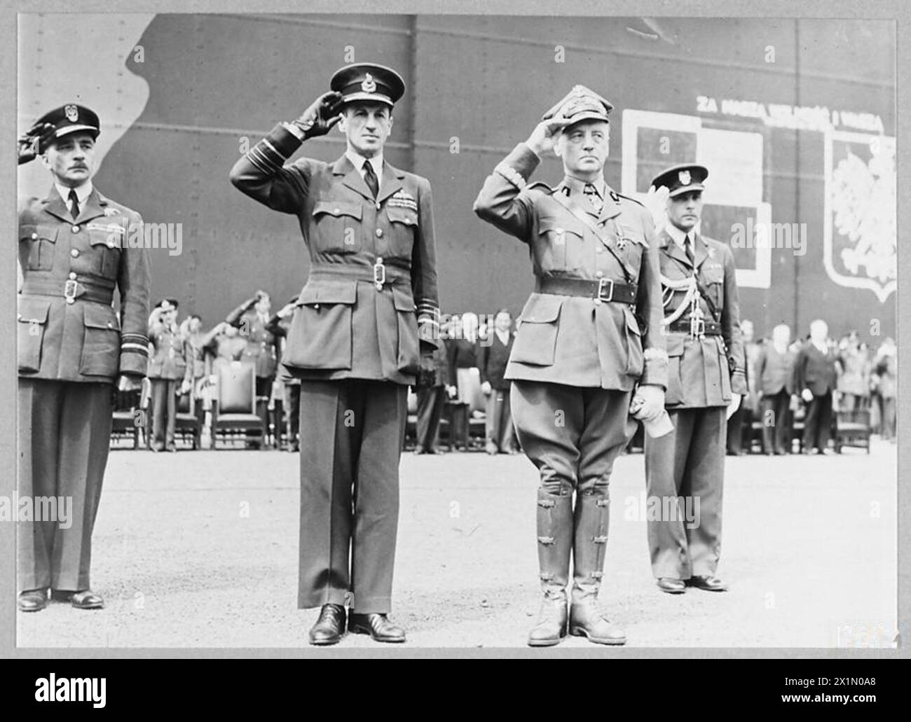 L'ARMÉE DE L'AIR POLONAISE EN GRANDE-BRETAGNE, 1940-1947 - la nouvelle norme de l'armée de l'air polonaise a été faite par des femmes et leurs familles à Wilno (Vilnius) en Pologne, alors sous occupation soviétique, et a été introduite clandestinement en Suède par des diplomates japonais d'où elle a finalement atteint la Grande-Bretagne en mars 1941. Le maréchal de l'air Charles Portal, commandant en chef du commandement des bombardiers de la RAF, et le général Władysław Sikorski, le C-en-C des Forces armées polonaises saluant la nouvelle cérémonie de présentation standard de l'armée de l'air polonaise à la RAF Swinderby, le 16 juillet 1941. Ils sont accompagnés du vice-maréchal de l'air Stanisław Ujejski, le général Banque D'Images