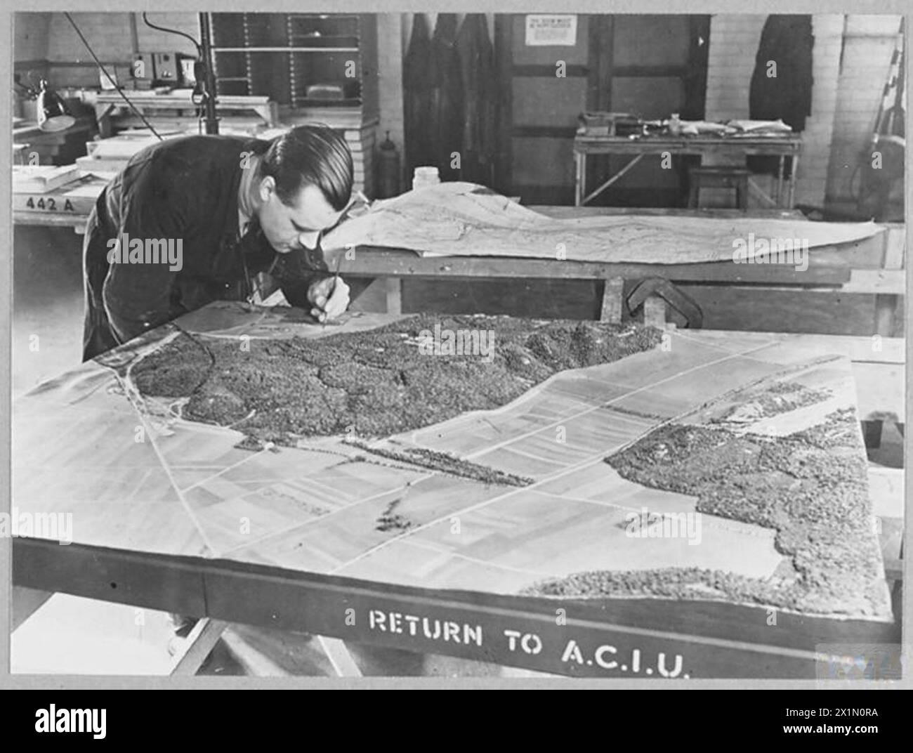 TRAVAIL D'UNE UNITÉ DE FABRICATION DE MAQUETTES R.A.F. - 15875 photo émise 1945 spectacles - après que la forme du terrain a été soigneusement vérifiée et corrigée, la 'peau' photographique est teinte avec les couleurs appropriées. Les routes, les voies ferrées, les rivières et les canaux sont peints. Les bâtiments déjà construits, les pylônes, les réservoirs de gaz et de pétrole, les arbres, les haies, etc., sont fermement appliqués à la surface. Les différents panneaux sont alors prêts à être assemblés, Royal Air Force Banque D'Images