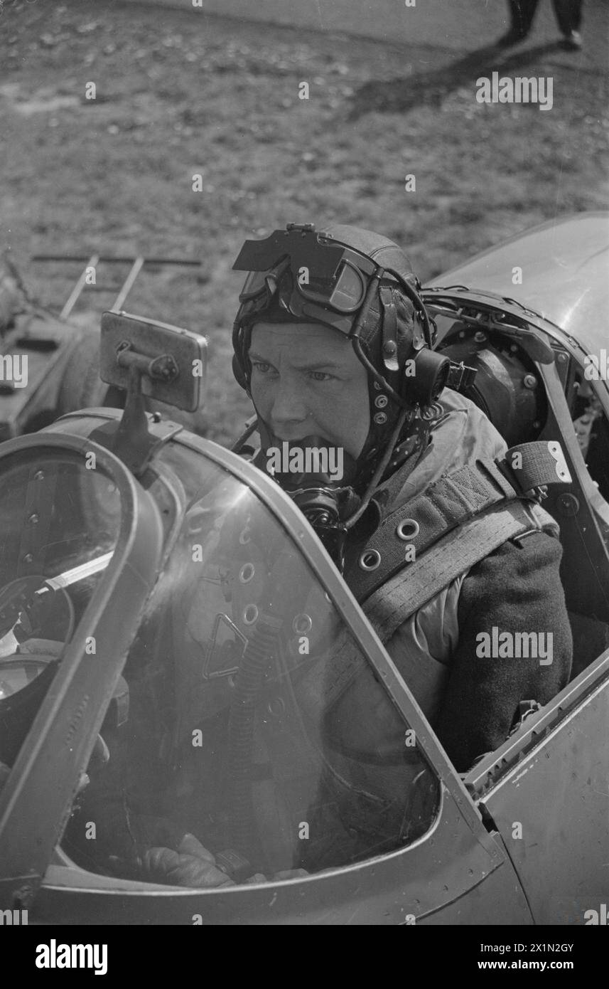 Un pilote de chasseur de la RAF se prépare méticuleusement dans le cockpit d'un Spitfire avec masque à oxygène, parachute, Mae West, lunettes foncées et capot en perspex avant un balayage. Banque D'Images