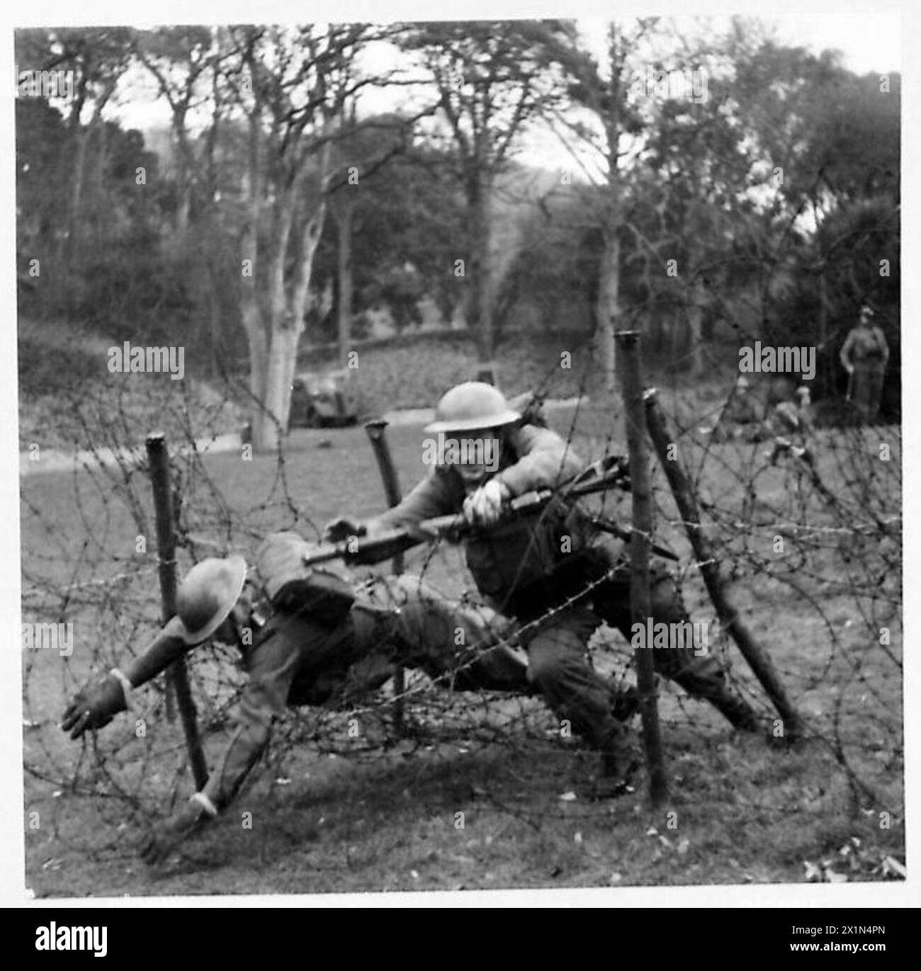 Deux soldats de l'armée britannique testent une méthode pour surmonter les obstacles en fil de fer barbelé pendant l'entraînement militaire. Banque D'Images
