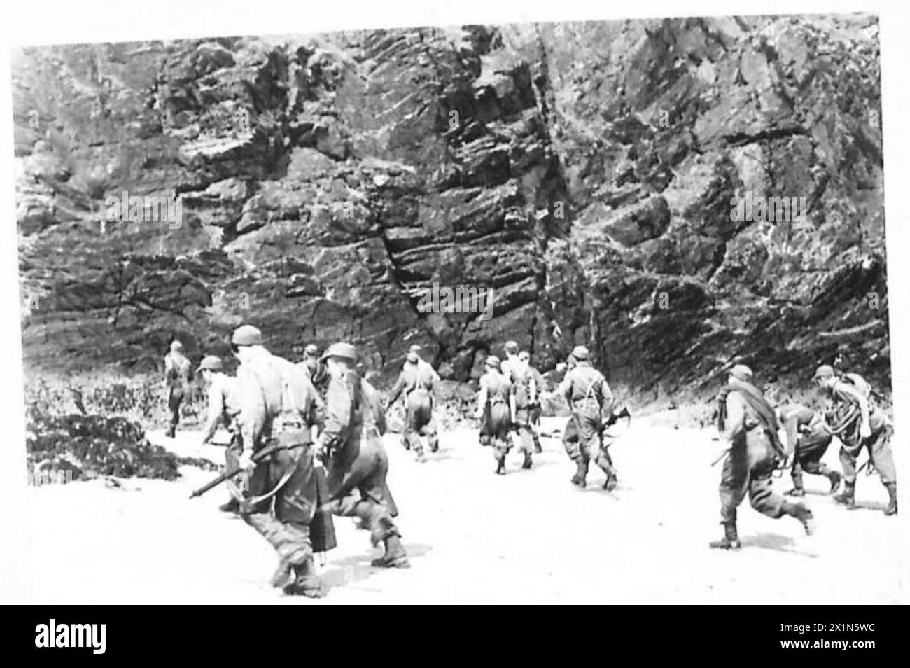 Une unité de l'armée britannique surnommée « les diables verts » traverse une plage pour attaquer une falaise lors d'une opération militaire. Banque D'Images