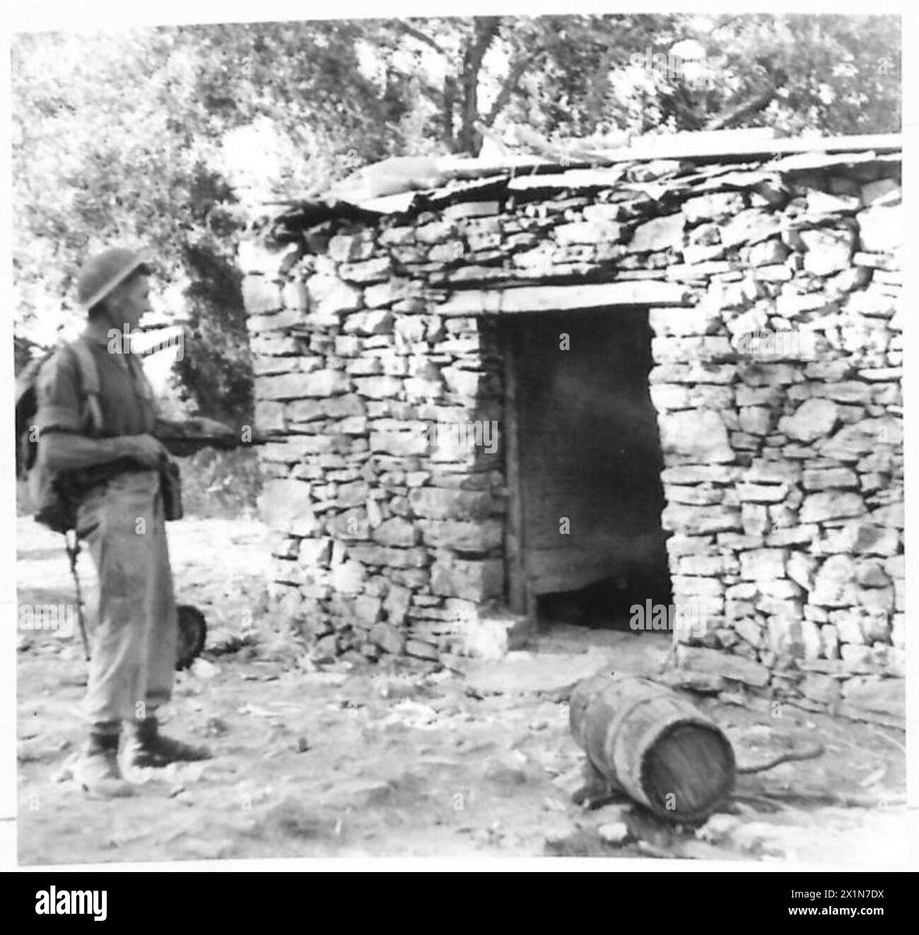 Un commando tire un fusil tommy de la hanche dans une porte de ferme lors d'un raid en Albanie sous la supervision de l'armée britannique. Banque D'Images
