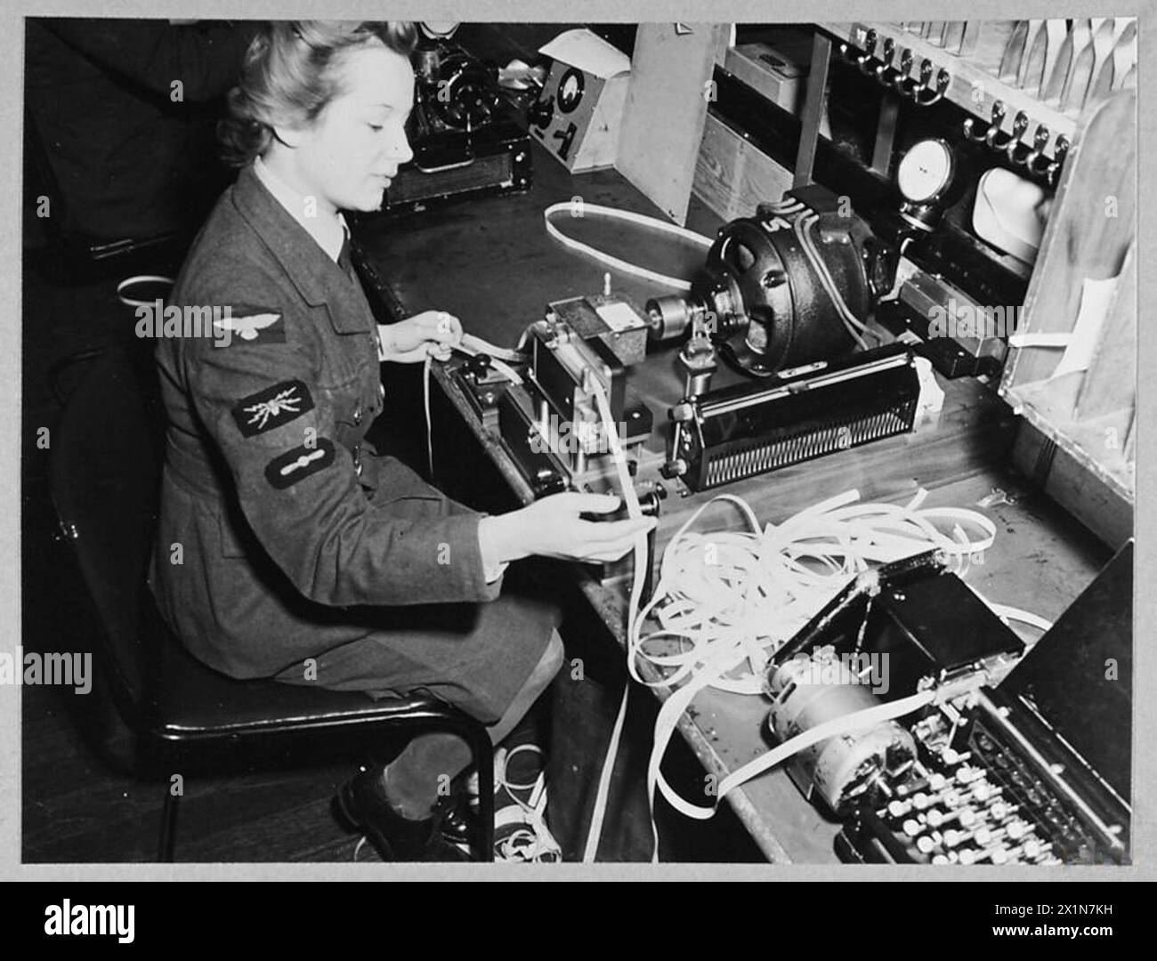 Le personnel de W.A.A.F. exploite les signaux de la RAF en transposant des messages en bande perforée pour le code Morse, envoyés via un émetteur automatique aux stations d'outre-mer à raison de 150 à 200 mots par minute, 1943. Banque D'Images