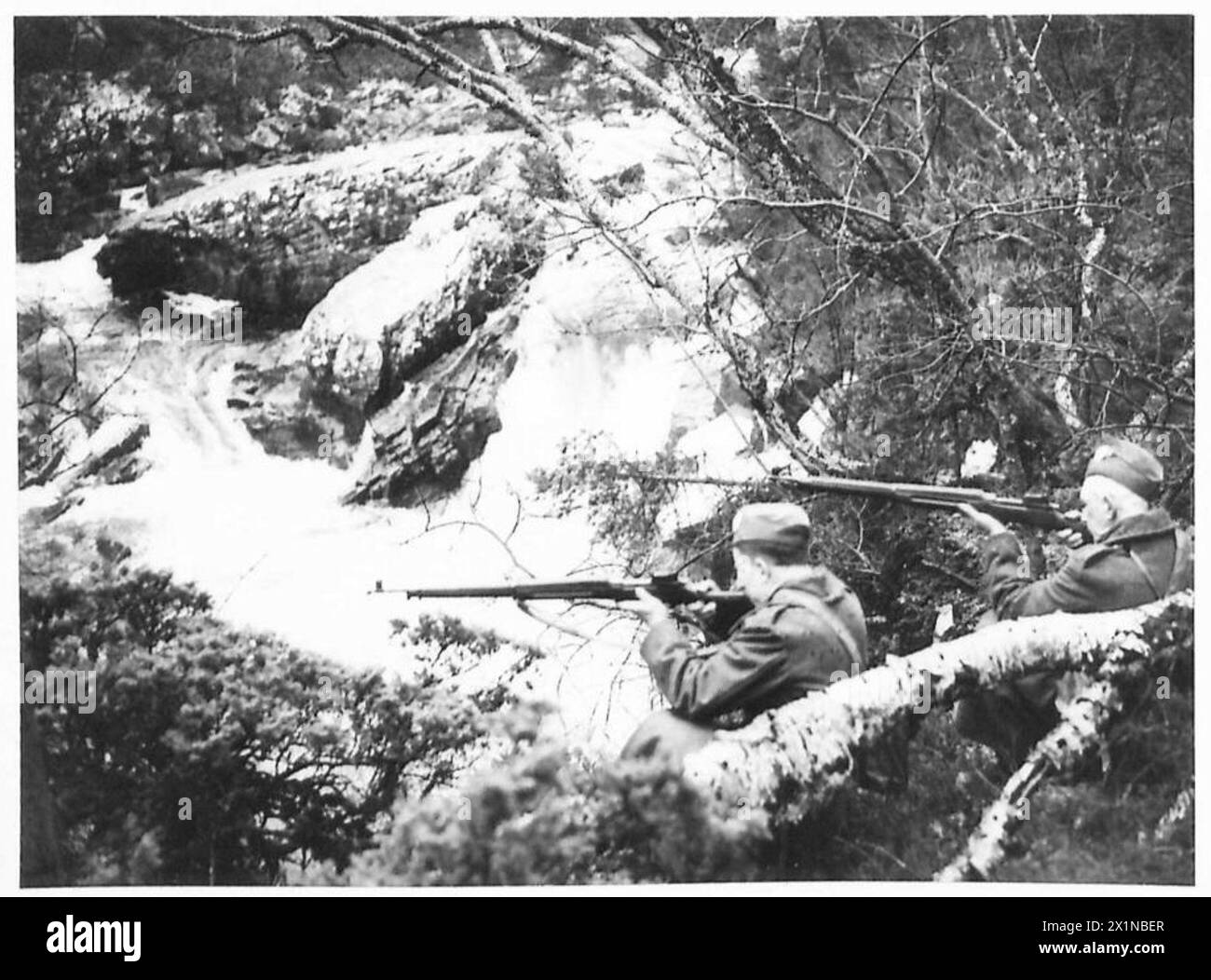 EXERCICE HOME GUARD DANS LE NORD DE L'ÉCOSSE - deux de la Home Guard en position de bord de route surplombant une cascade à Glen Moriston. C'est typique du pays dans lequel ils opèrent, l'armée britannique Banque D'Images