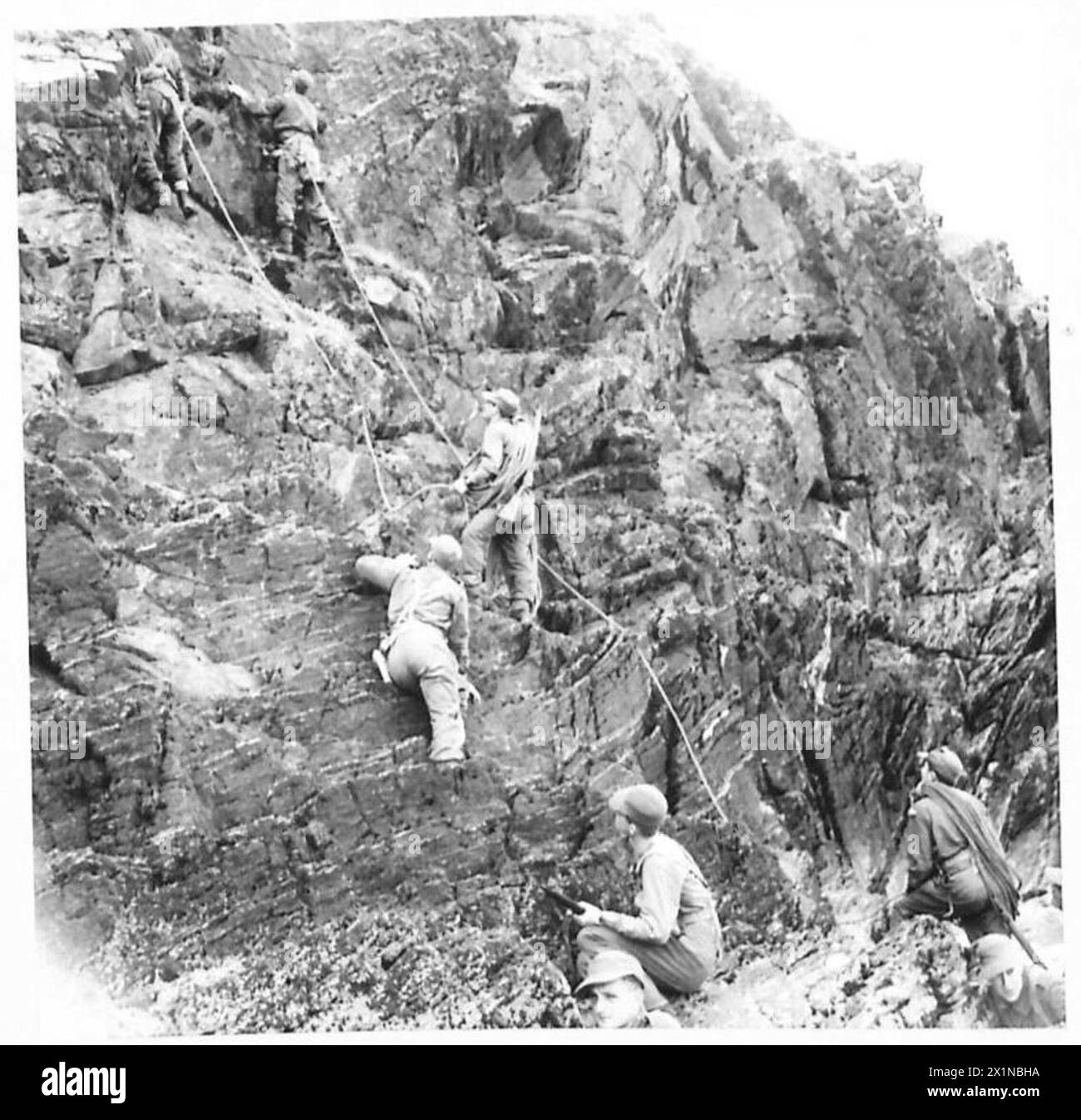 L'avant-garde du personnel de l'armée britannique grimpe une falaise difficile tandis que le groupe principal attend en contrebas. Banque D'Images