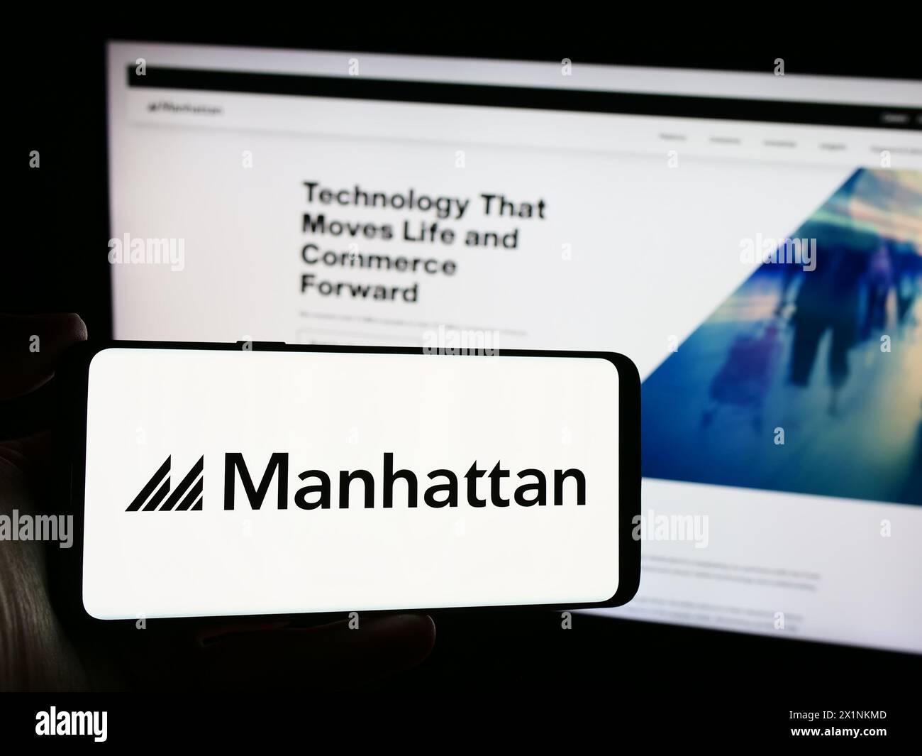 Personne tenant le téléphone portable avec le logo de la société américaine de logiciels Manhattan Associates Inc en face de la page Web. Concentrez-vous sur l'affichage du téléphone. Banque D'Images