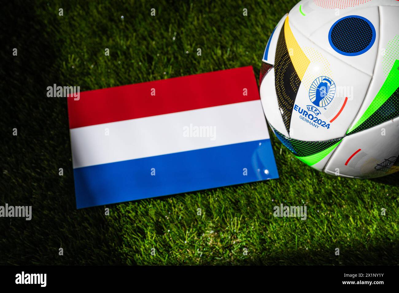 BERLIN, ALLEMAGNE, 17 AVRIL 2024 : drapeau national néerlandais et ballon de football officiel du tournoi de football Euro 2024 en Allemagne placé sur l'herbe verte. Banque D'Images