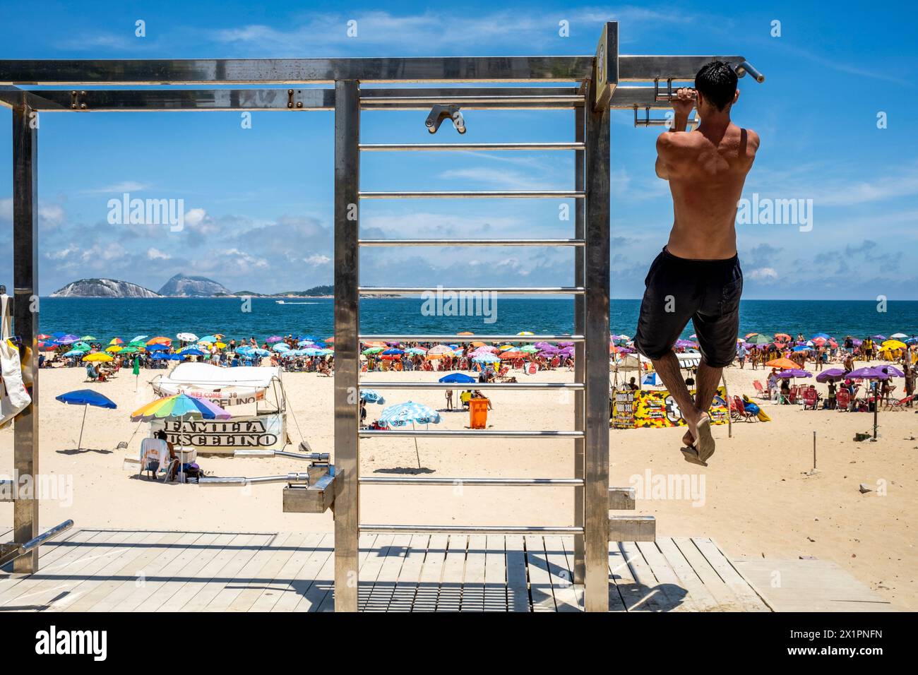 Un jeune homme faisant des tractions dans une station d'exercice sur la plage d'Ipanema, Ipanema, Rio de Janeiro, Brésil. Banque D'Images