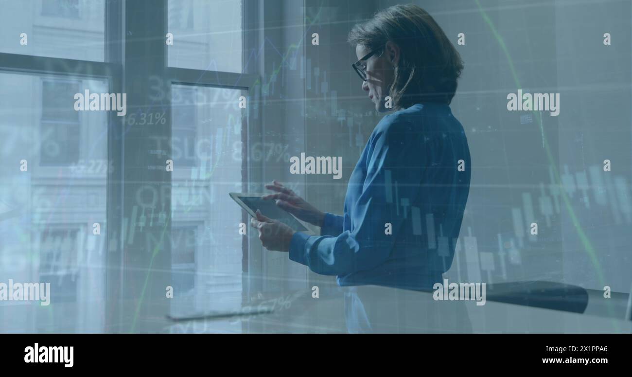 Une femme caucasienne d'âge moyen, portant des lunettes, examine un comprimé Banque D'Images