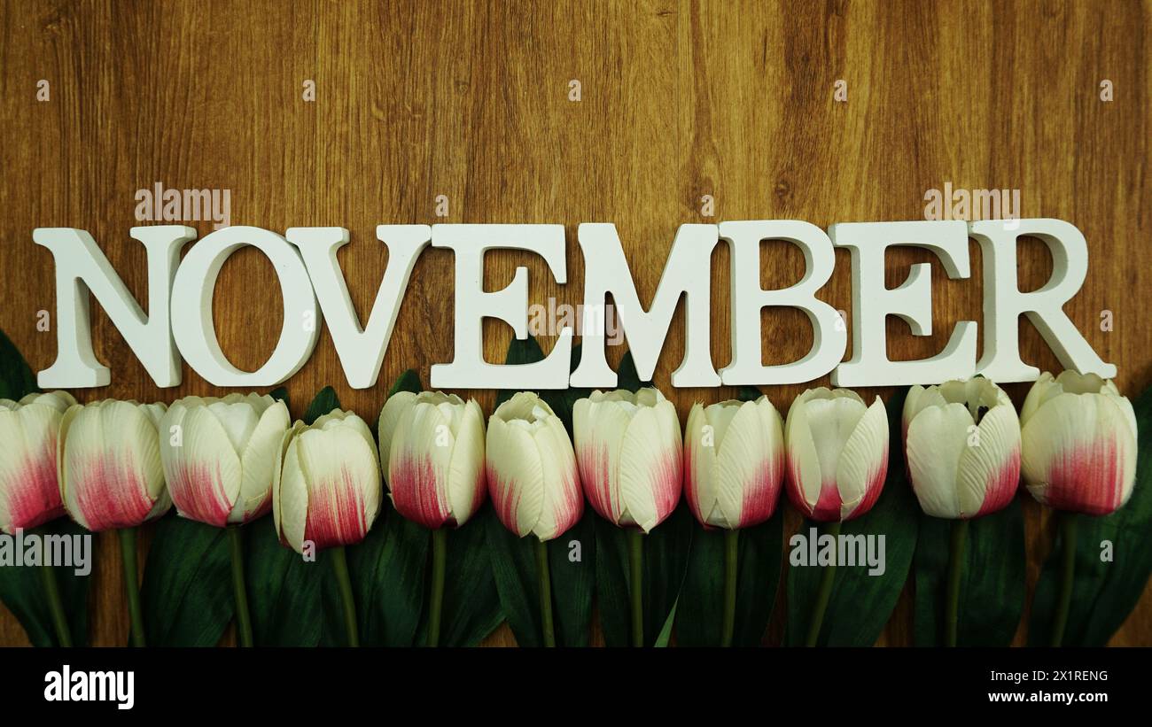 lettres de l'alphabet de novembre avec bouquet de fleurs sur fond de bois Banque D'Images