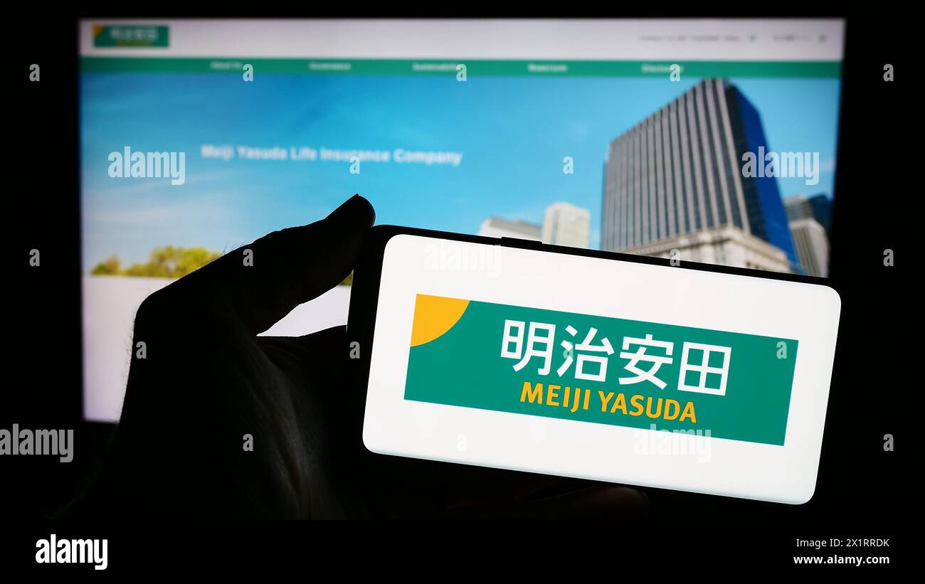 Personne tenant un smartphone avec le logo de l'entreprise japonaise Meiji Yasuda Life Insurance Company en face du site Web. Concentrez-vous sur l'affichage du téléphone. Banque D'Images