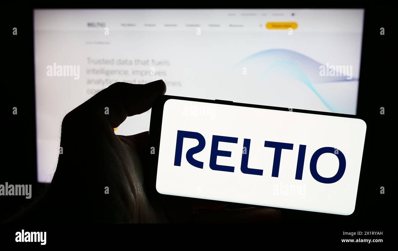 Personne tenant un smartphone avec le logo de la société de logiciels américaine Reltio Inc en face du site Web. Concentrez-vous sur l'affichage du téléphone. Banque D'Images