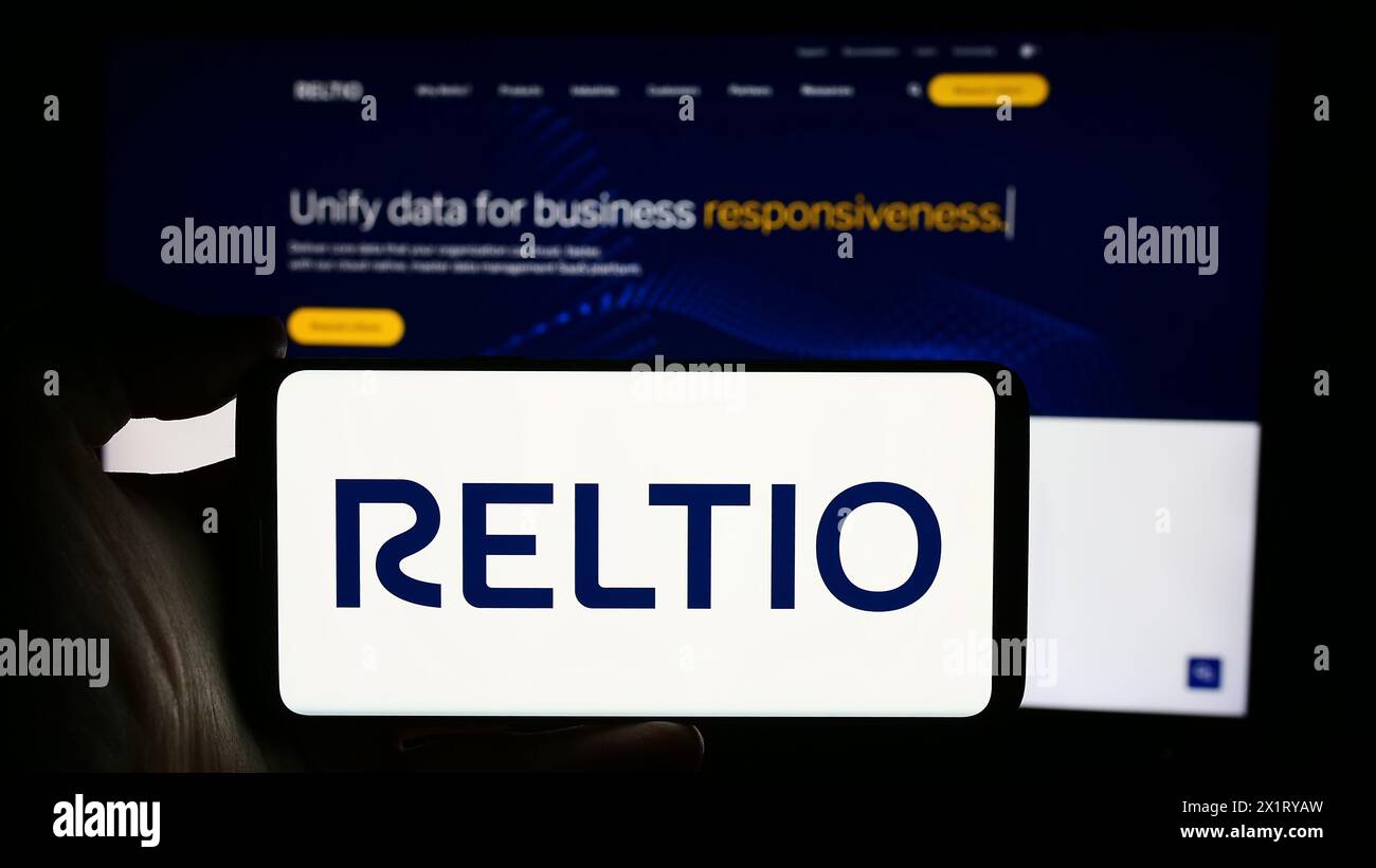 Personne tenant le téléphone portable avec le logo de la société de logiciels américaine Reltio Inc. devant la page Web de l'entreprise. Concentrez-vous sur l'affichage du téléphone. Banque D'Images