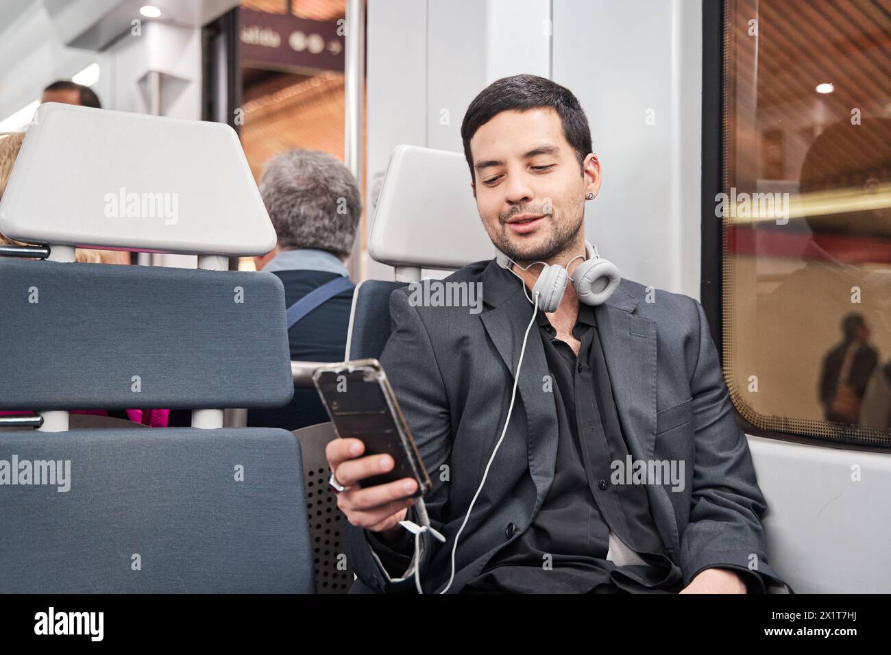 homme latino assis dans le train en utilisant son téléphone intelligent tout en voyageant dans les transports publics Banque D'Images