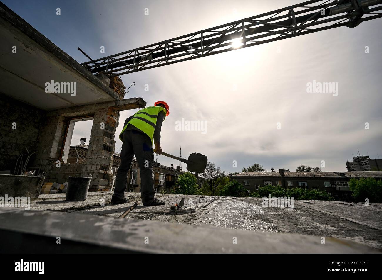 ZAPORIZHZHIA, UKRAINE - 17 AVRIL 2024 - Un travailleur avec une bêche est vu au travail alors que le bâtiment résidentiel au 80 rue Nezalezhnoi Ukrainy/3 rue Yakova Novytskoho détruit par les bombardements russes est en reconstruction, Zaporizhzhia, dans le sud-est de l'Ukraine. Banque D'Images