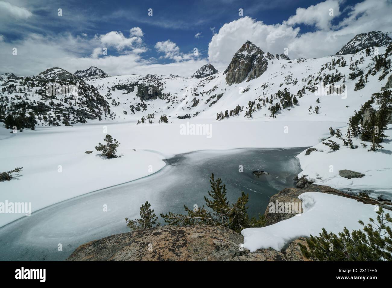 Pacific Crest Trail. Une belle chaîne de montagnes avec un lac au premier plan. Le lac est gelé et entouré de neige. Le ciel est clair et bl Banque D'Images