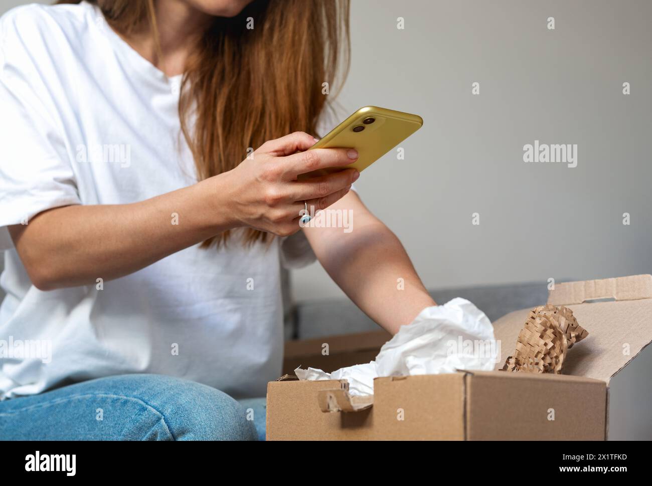 Livraison express. Réception d'un achat en ligne. Femme déballer le carton et prendre des photos des achats. Banque D'Images Livraison express. Réception d'un achat en ligne. Femme déballer le carton et prendre des photos des achats. Banque D'Images