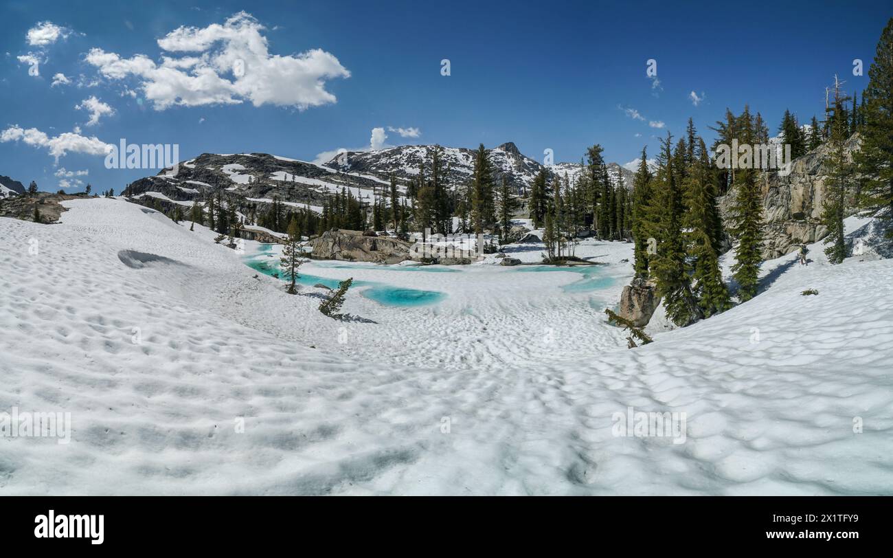 Pacific Crest Trail. Un paysage enneigé avec un lac bleu au milieu. Le ciel est clair et le soleil brille Banque D'Images