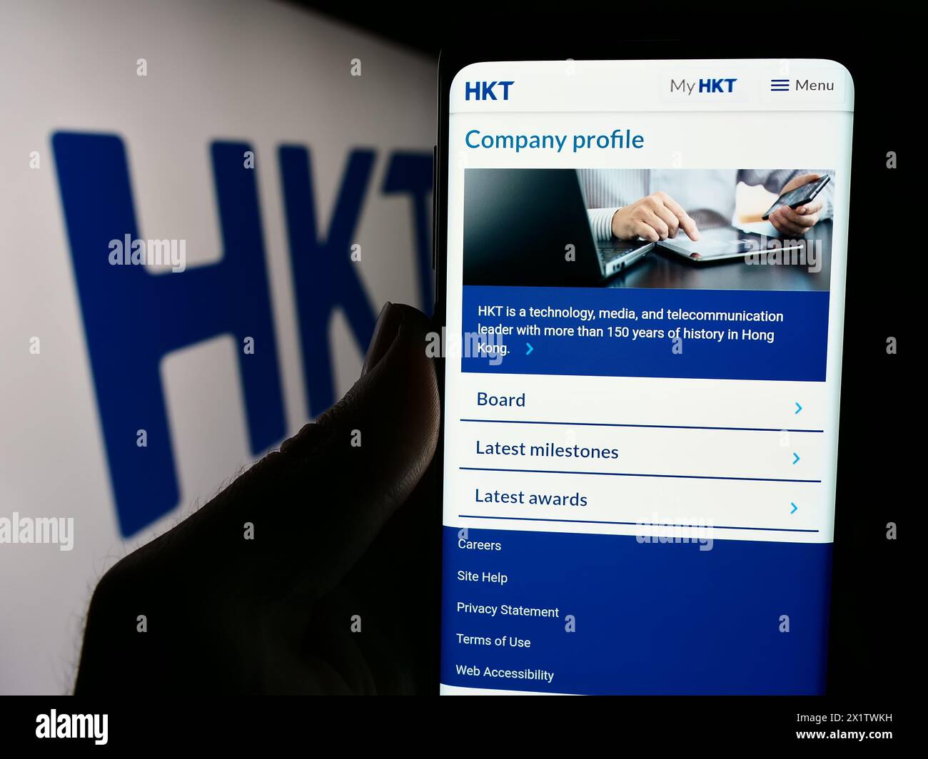 Personne tenant smartphone avec page Web de la société de télécommunications HKT Limited (Hong Kong Telecom) avec logo. Concentrez-vous sur le centre de l'écran du téléphone. Banque D'Images