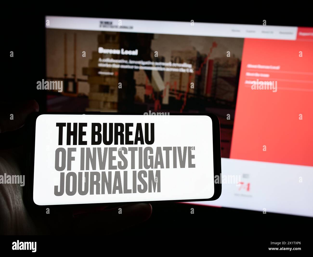 Personne tenant le téléphone portable avec le logo de l'organisation le Bureau du journalisme d'investigation (TBIJ) en face de la page Web. Concentrez-vous sur l'affichage du téléphone. Banque D'Images