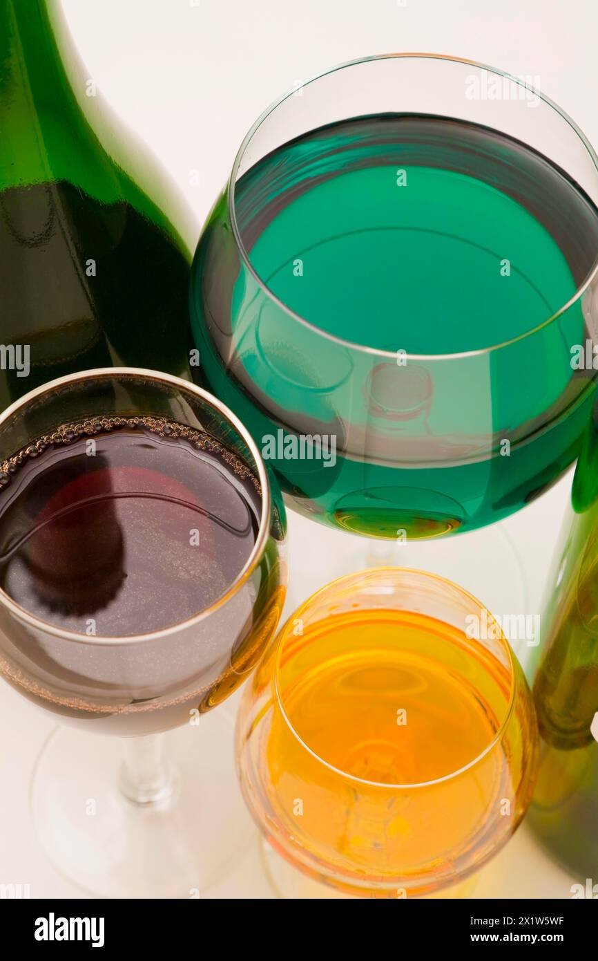 Gros plan verres à boire en verre clair de différentes tailles remplis de liqueurs alcoolisées vertes, jaunes et rouges assorties sur fond blanc, Studio Banque D'Images