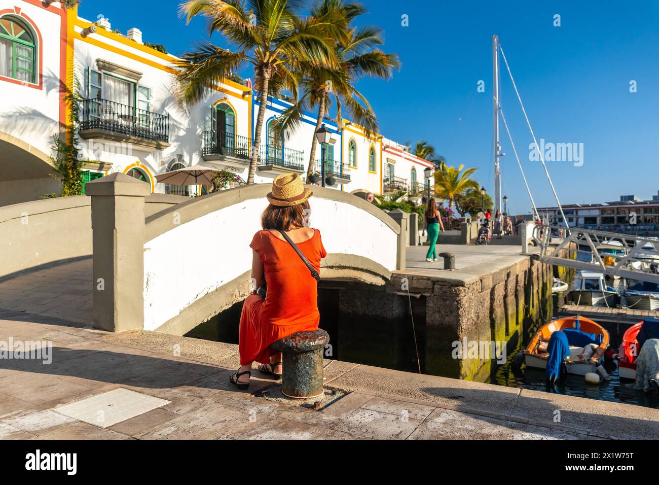 Une femme touriste dans une robe rouge assis dans le port de la ville Mogan à Gran Canaria en été Banque D'Images