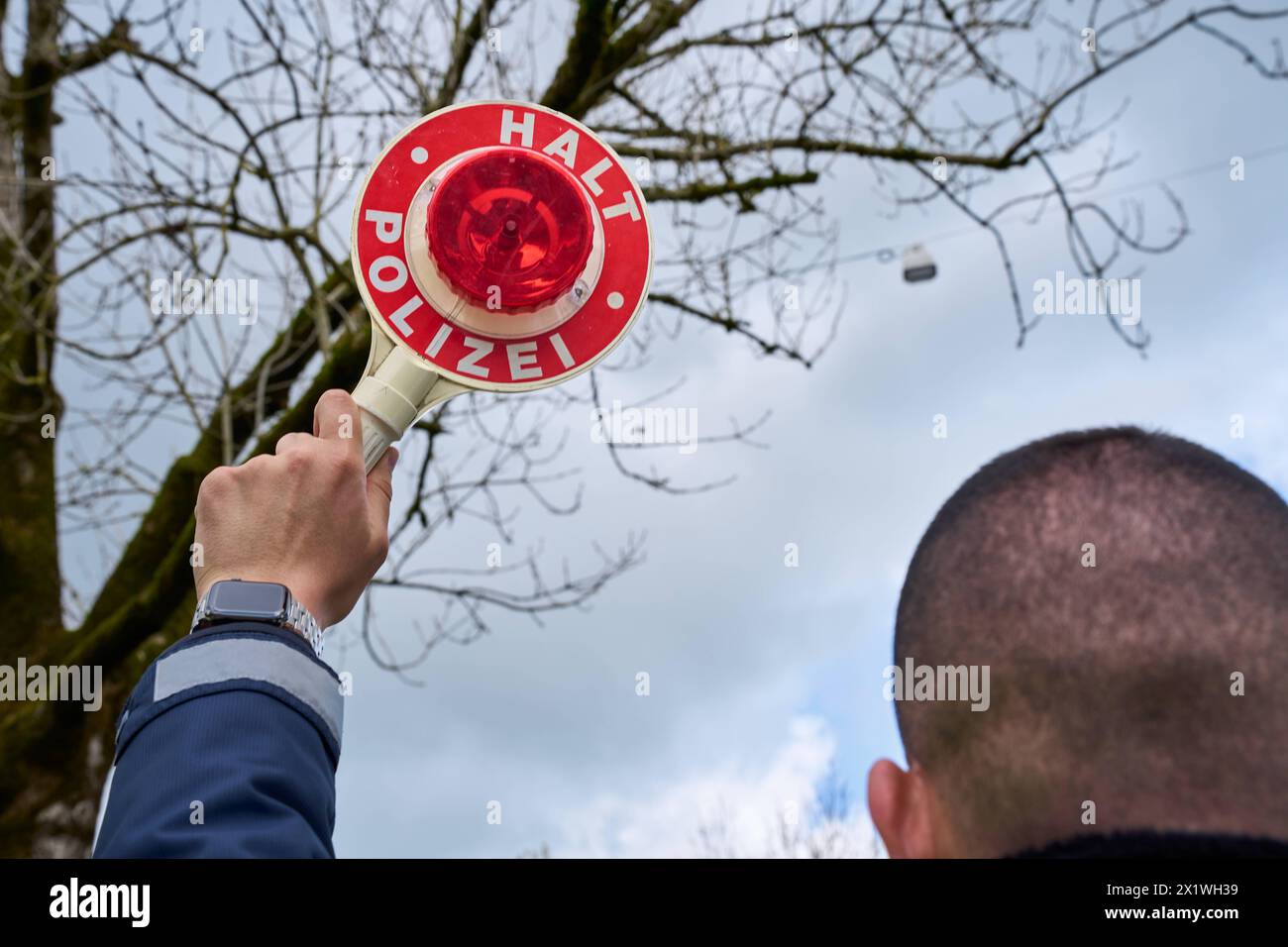 Augsbourg, Bavière, Allemagne - 17 avril 2024 : officier de police tenant une truelle de police portant l'inscription Halt Polizei *** Polizist hält eine Polizeikelle mit Aufschrift halt Polizei Banque D'Images