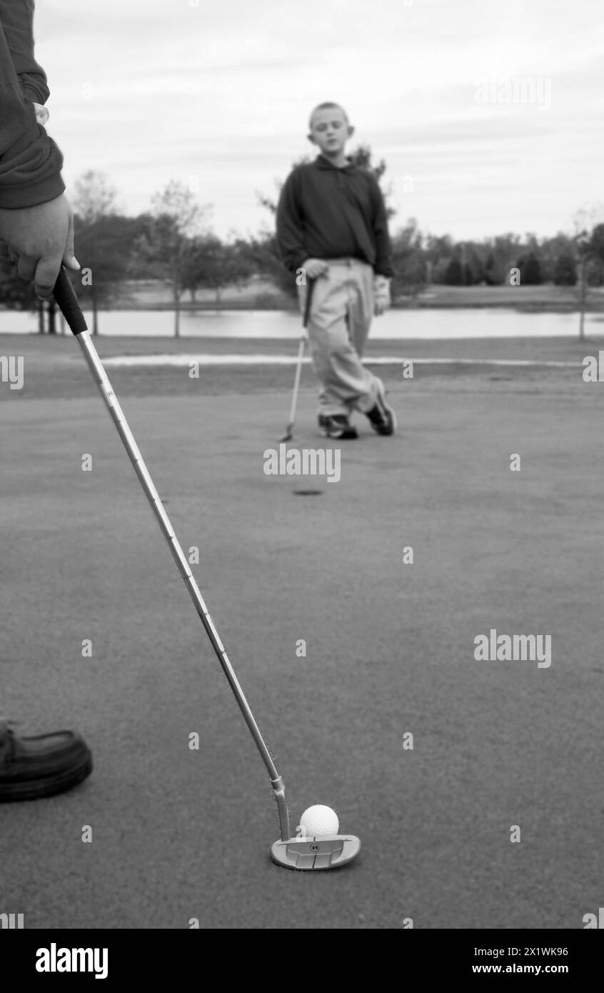 Jeune golfeur masculin caucasien attendant de jouer comme un autre golfeur putts, États-Unis. Banque D'Images