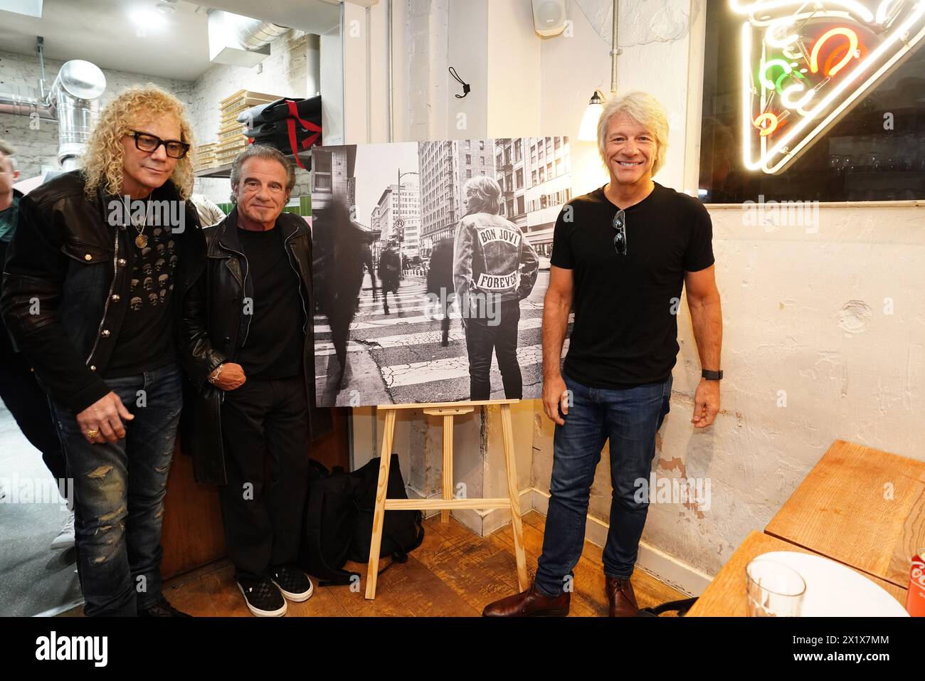 David Bryan, Tico Torres, et Jon bon Jovi du groupe de rock américain bon Jovi avec des fans lors d'une soirée pizza et d'un événement d'écoute pour leur nouvel album 'Forever' dans le centre de Londres. Les fans invités à l'événement d'écoute pour l'album, qui sort le 7 juin, ont été surpris lorsque leurs idoles de musique ont rejoint le London Gathering. Date de la photo : jeudi 18 avril 2024. Banque D'Images