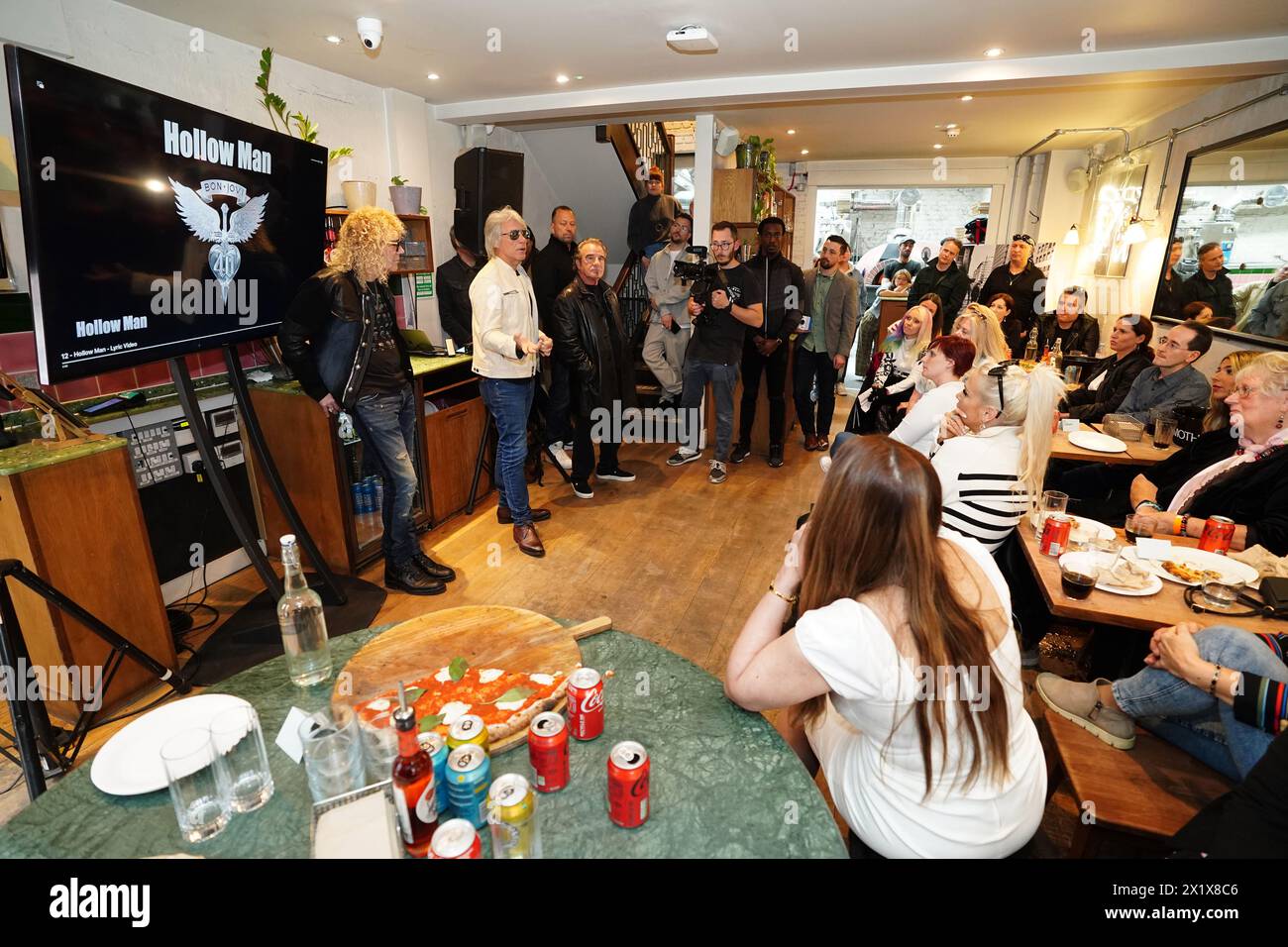 David Bryan, Jon bon Jovi, et Tico Torres du groupe de rock américain bon Jovi avec des fans lors d'une soirée pizza et d'un événement d'écoute pour leur nouvel album 'Forever' dans le centre de Londres. Les fans invités à l'événement d'écoute pour l'album, qui sort le 7 juin, ont été surpris lorsque leurs idoles de musique ont rejoint le London Gathering. Date de la photo : jeudi 18 avril 2024. Banque D'Images