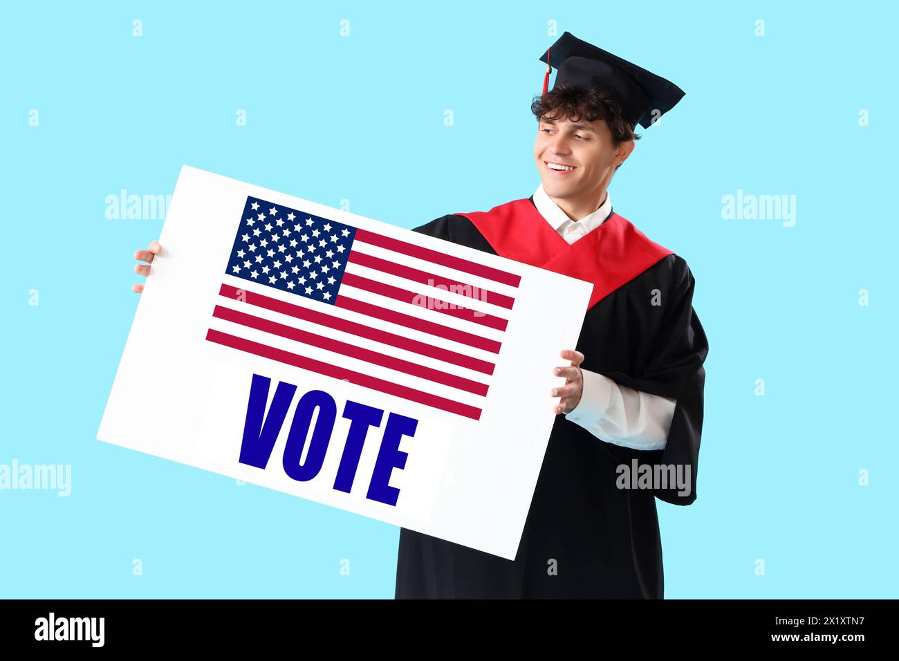 Étudiant diplômé masculin tenant une affiche avec VOTE DE mot et drapeau des États-Unis sur fond bleu clair Banque D'Images