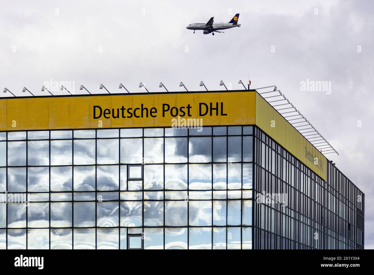 Aéroport international de Francfort, Allemagne - 19 février 2024 : un avion survolant un bâtiment de la marque 'Deutsche Post DHL' et un f Banque D'Images