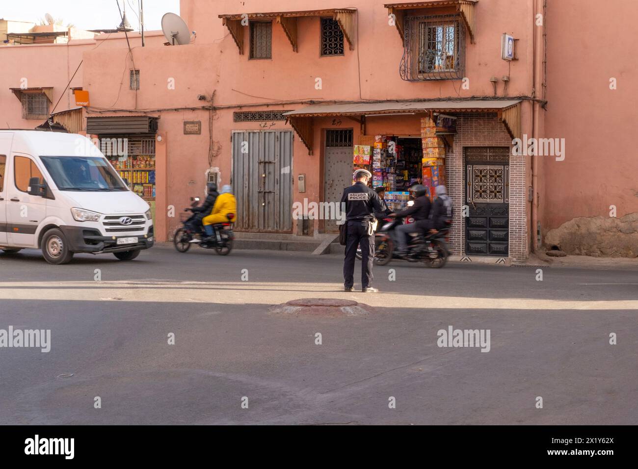 Policier enquêtant sur le crime, parle aux résidents, scène captivante vie urbaine africaine authentique à Marrakech, Maroc - 7 janvier 2024 Banque D'Images