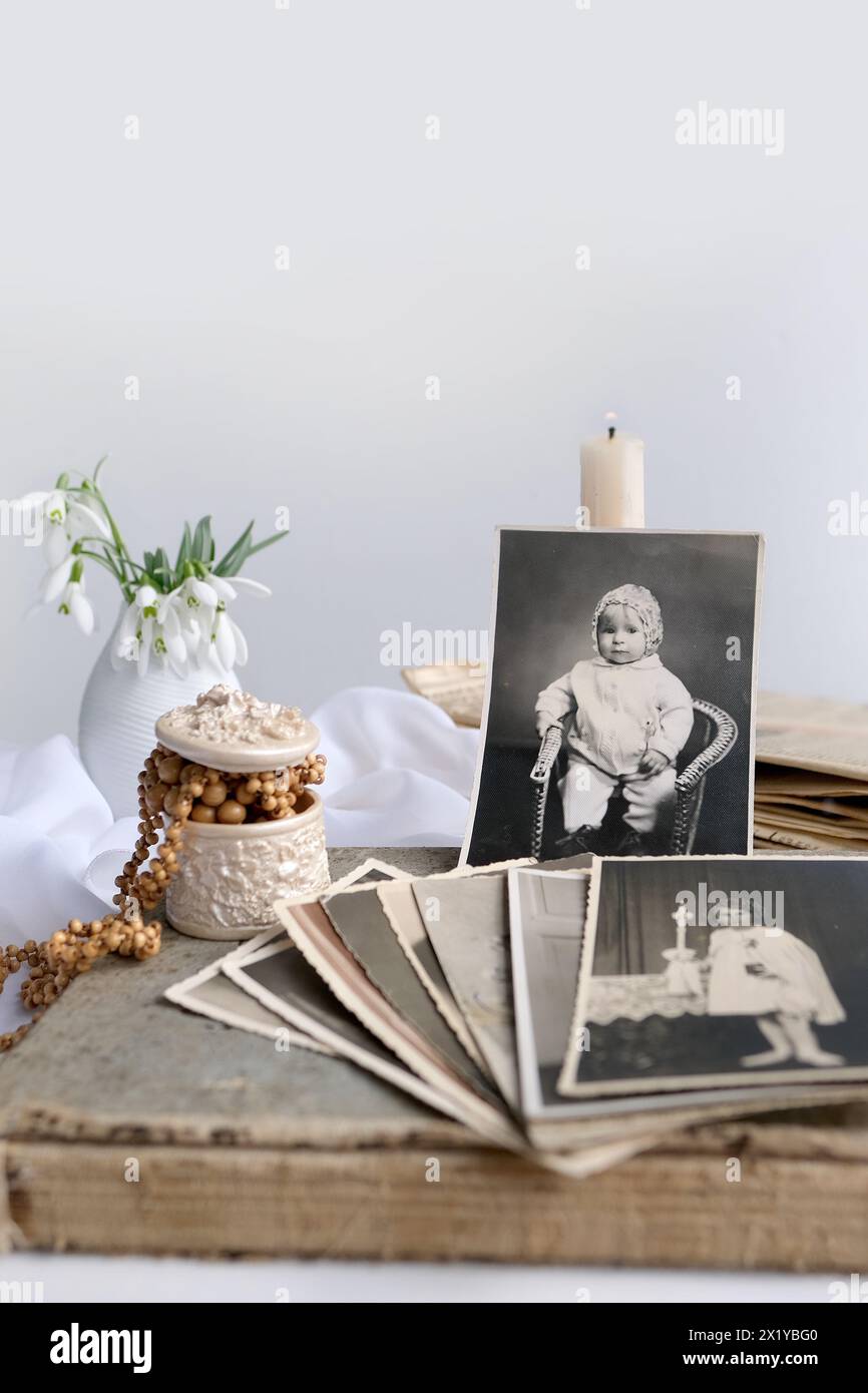 pile de photos vintage, images d'enfants de la première communion de 1950, bougie allumée, fleurs de printemps dans un vase, concept d'arbre généalogique, généalogie, ch Banque D'Images